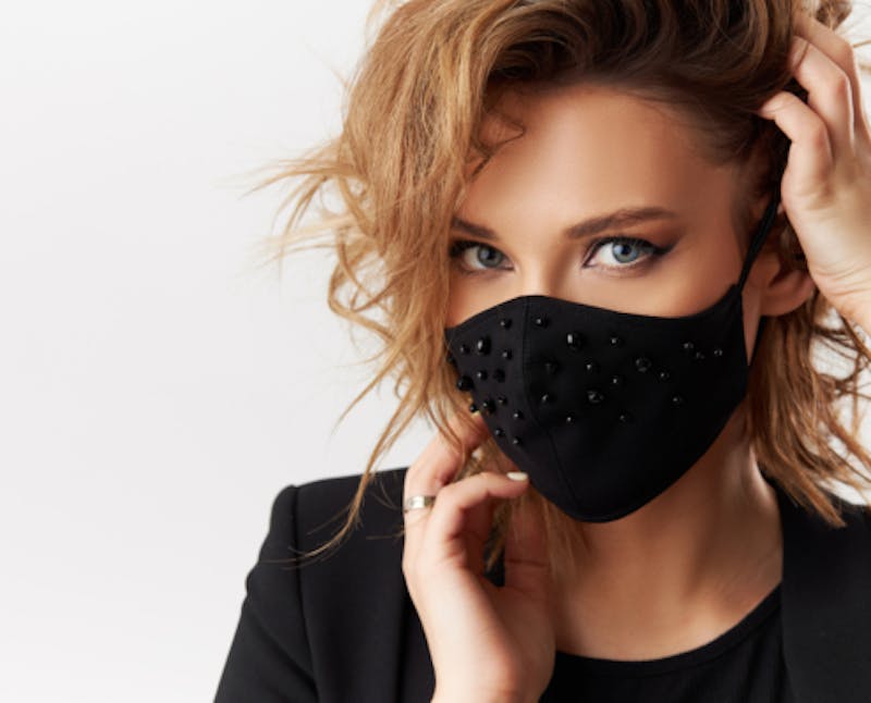blond woman with blue eyes wearing a black mask and black shirt
