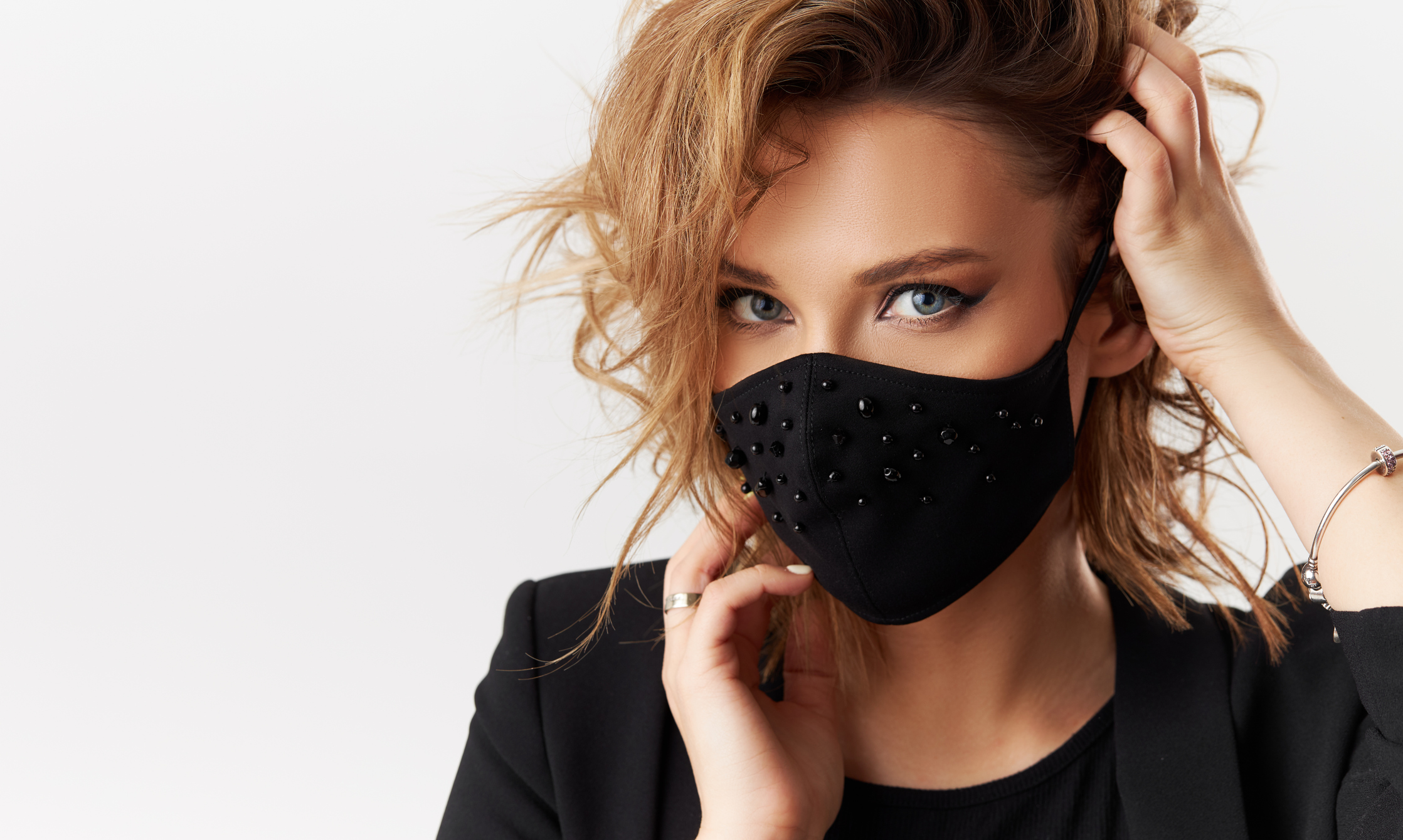 blond woman with blue eyes wearing a black mask and black shirt