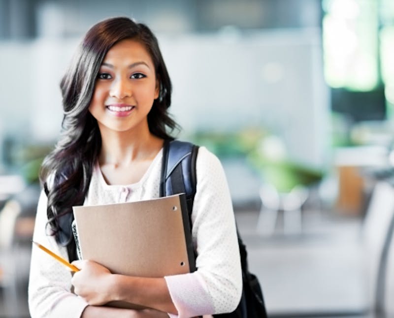 smiling woman with backpack and notebook standing in an college