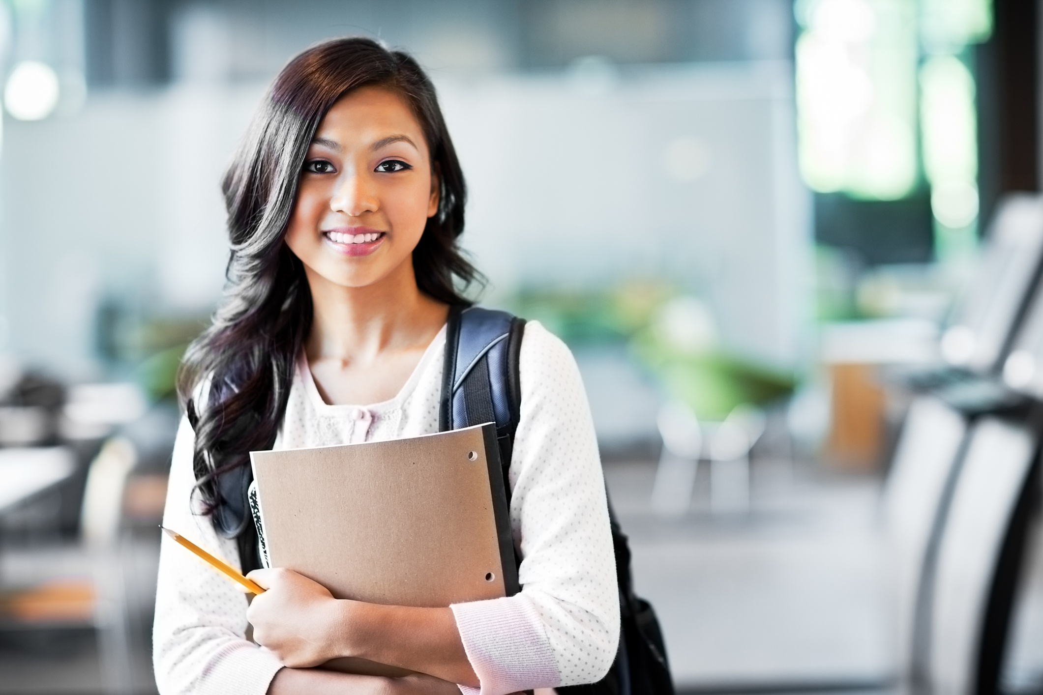 smiling woman with backpack and notebook standing in an college