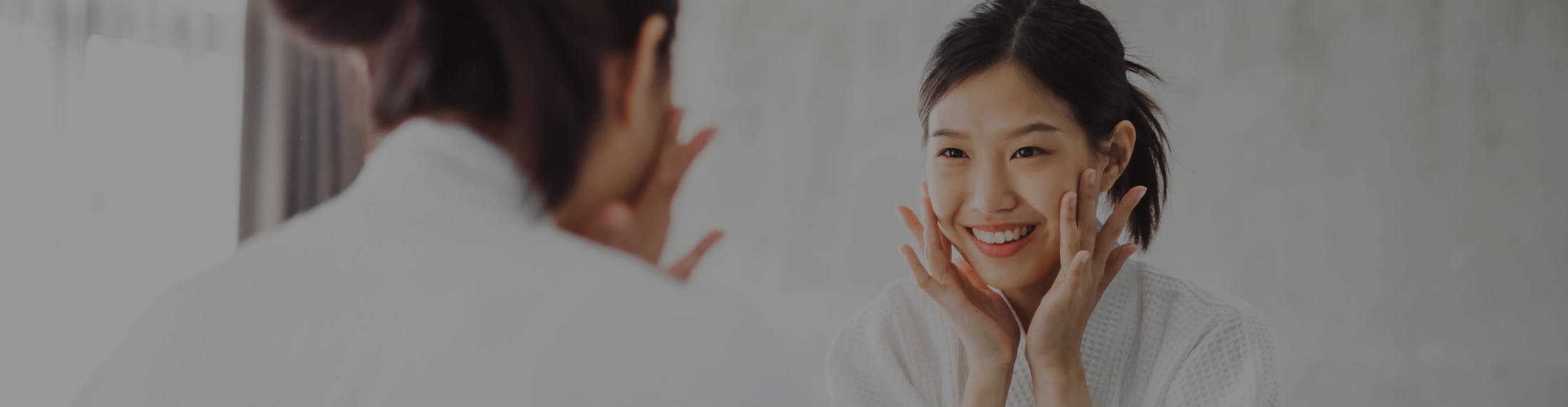 woman that is looking at her face in the mirror