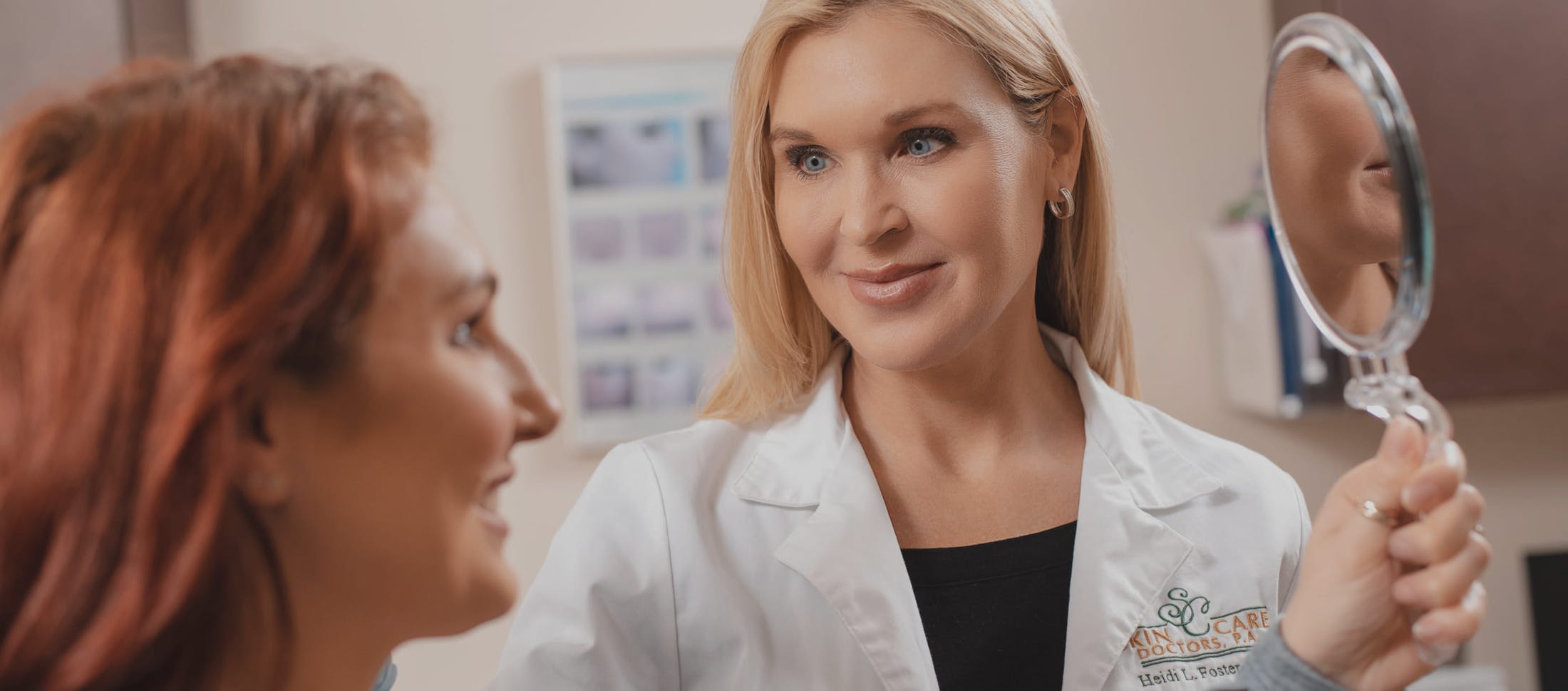 Female doctor holding up a mirror for a female patient to look into