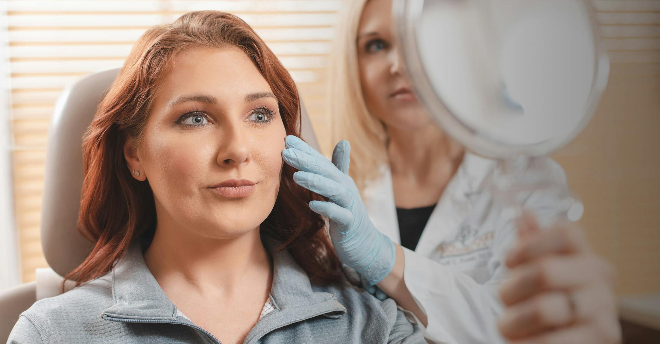 Female patient with red hair looking into a handheld mirror