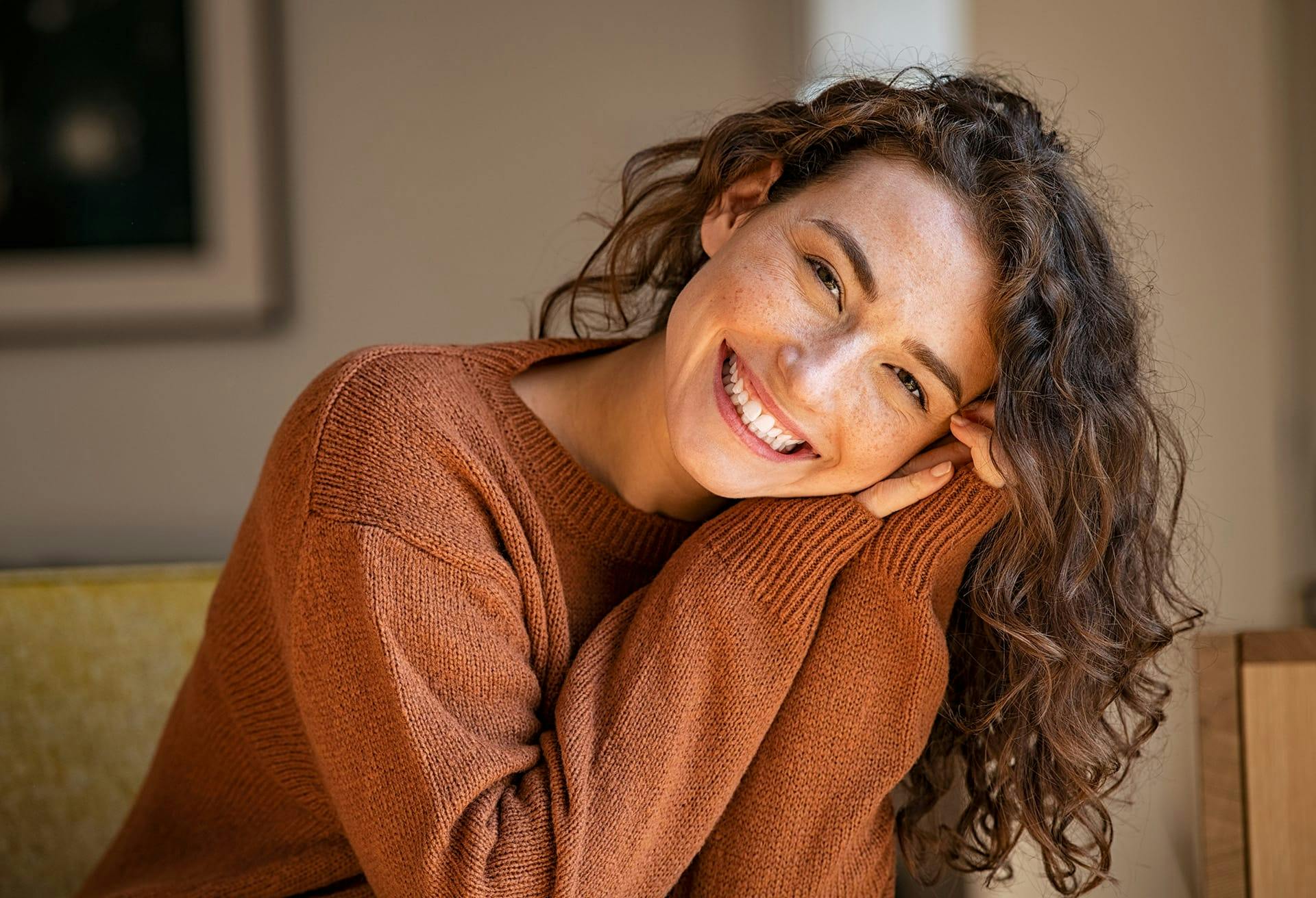 Woman smiling wearing a brown sweater