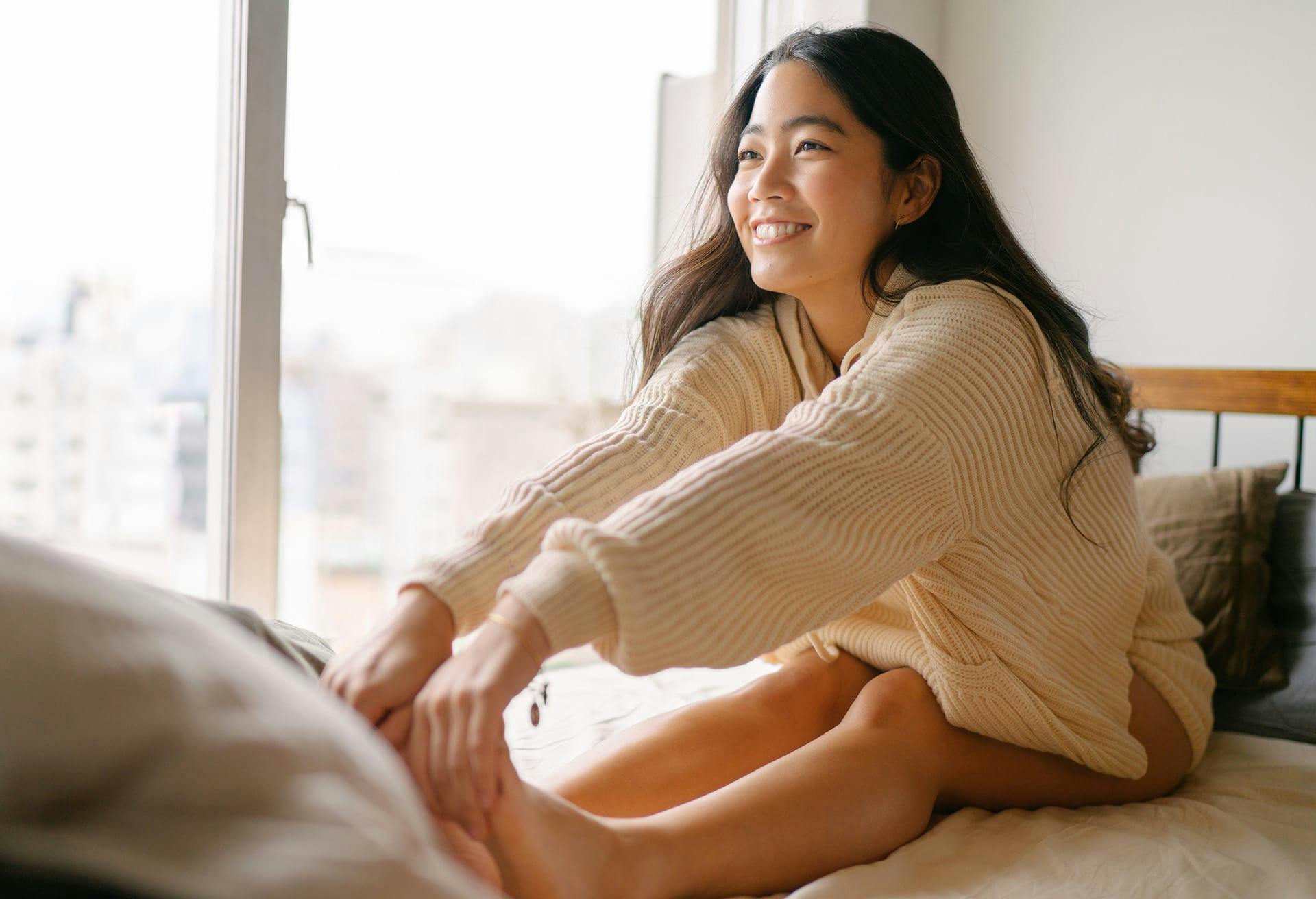 there is a woman sitting on a bed stretching her legs