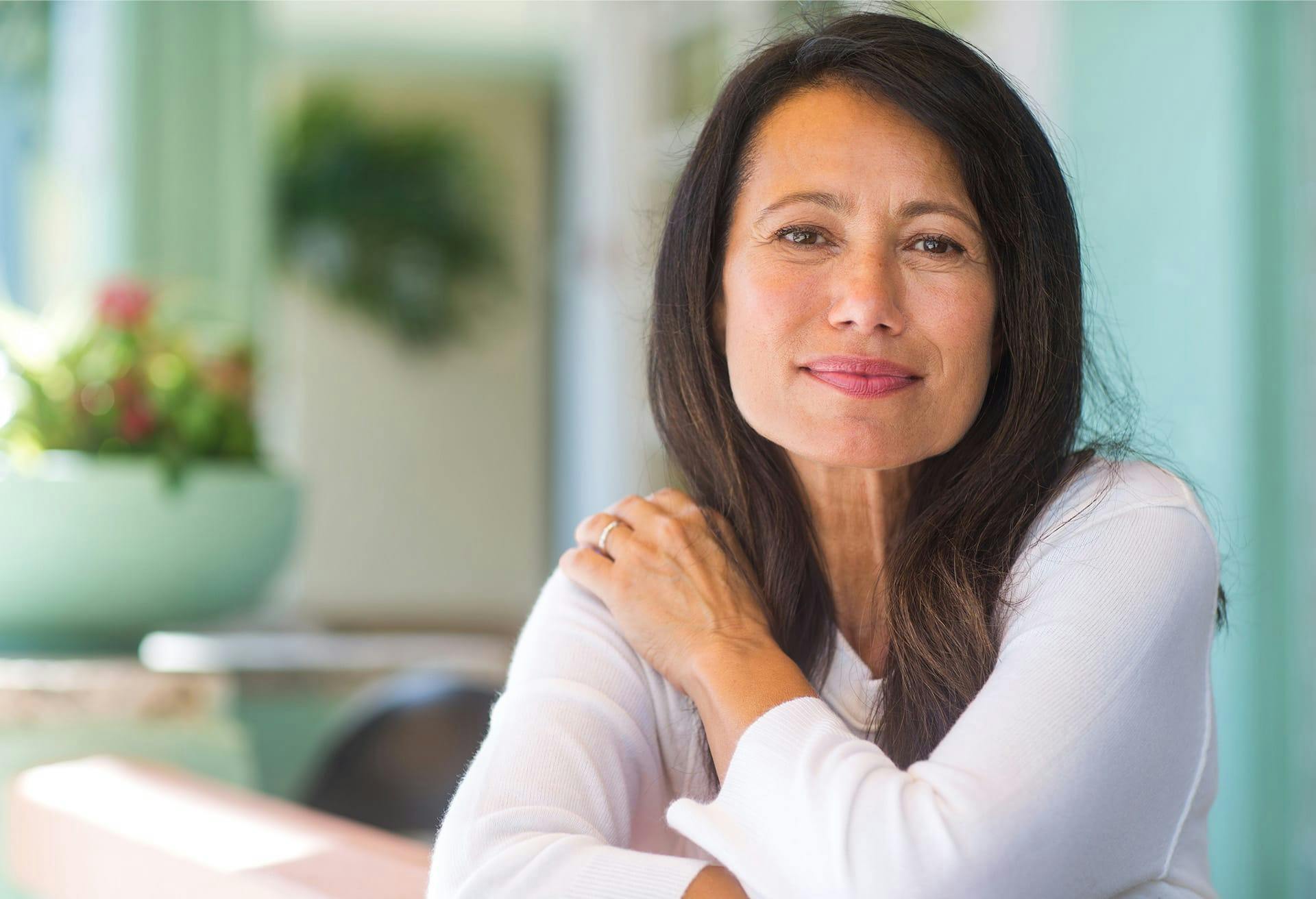 Woman with long dark hair wearing a long sleeve white top