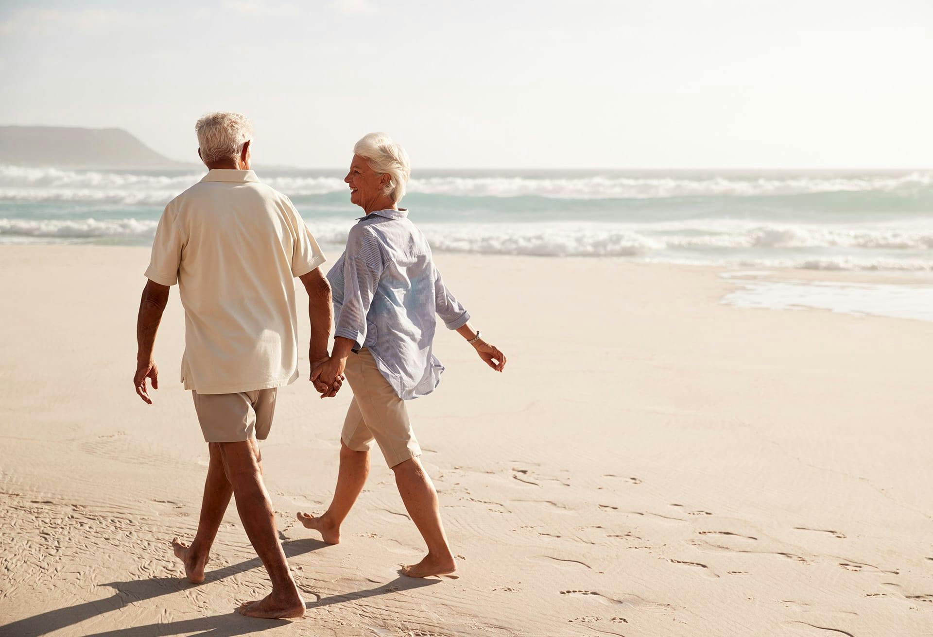 older couple walking on the beach holding hands