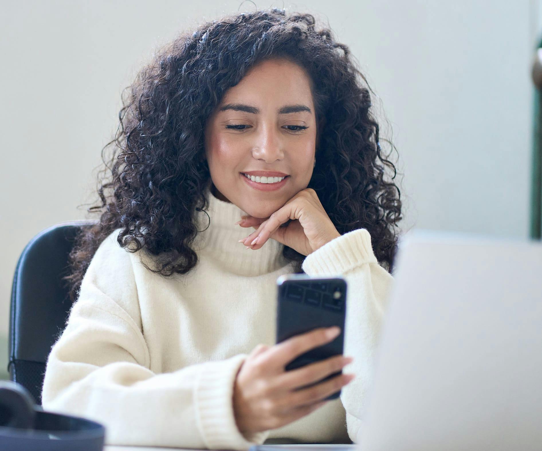 woman sitting at a table with a laptop and cell phone