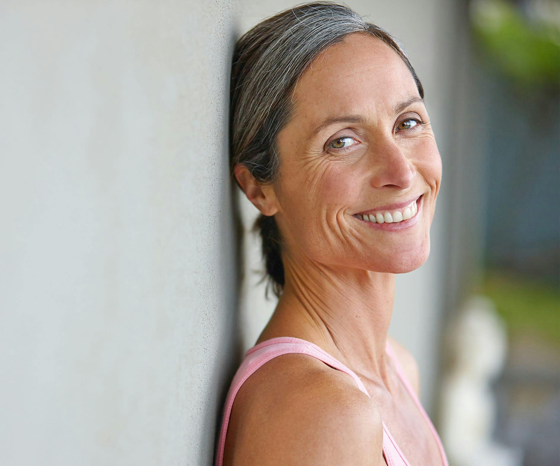 Woman smiling while leaning against a wall