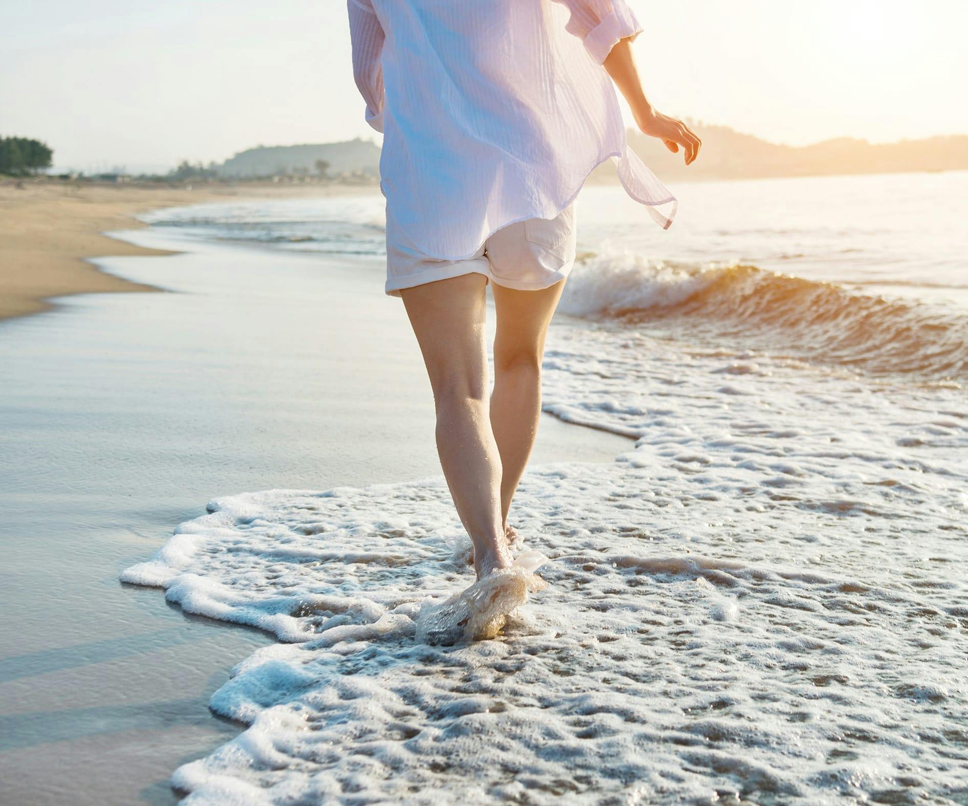 person walking on the beach with their feet in the water