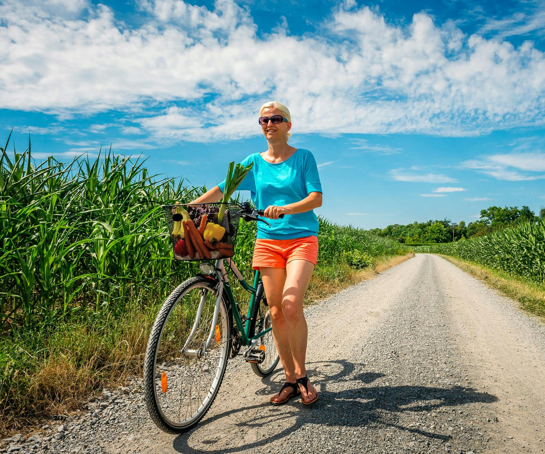 woman standing next to a bicycle on a dirt road