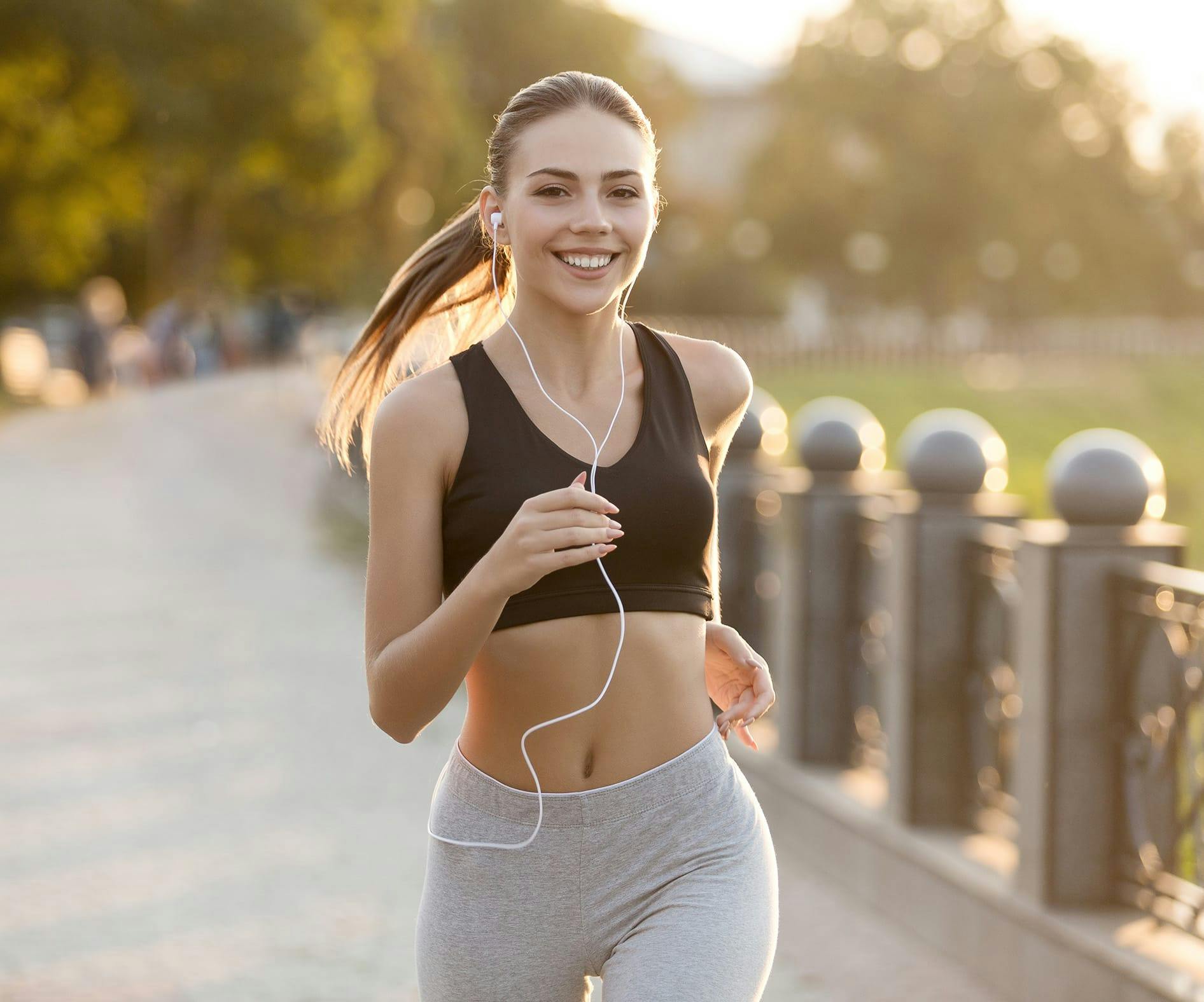 woman running in a park with earphones in her ears