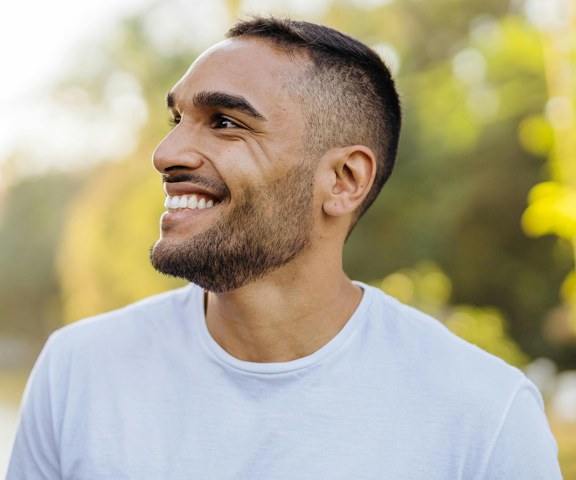 smiling man with beard and white shirt looking to the side