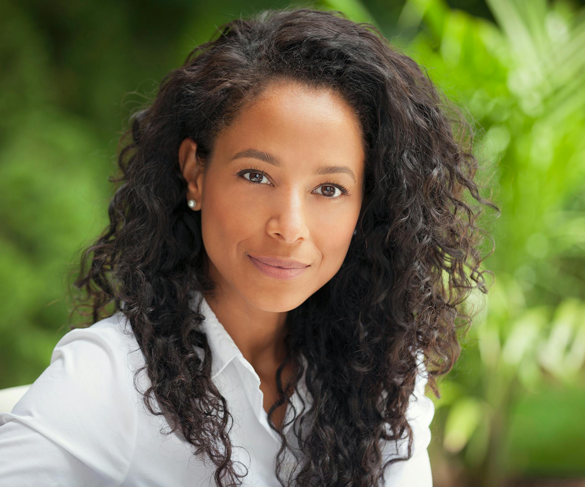a woman with long curly hair posing for a picture