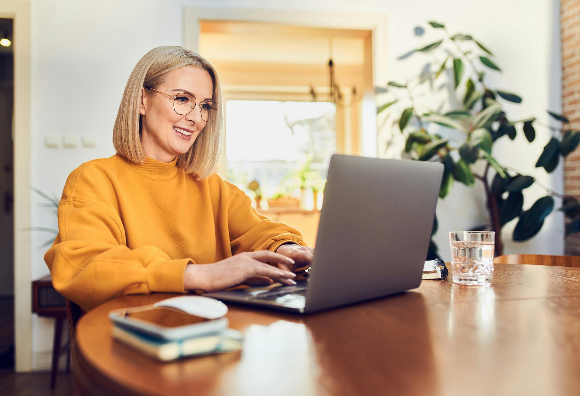 smiling woman sitting at a table with a laptop computer