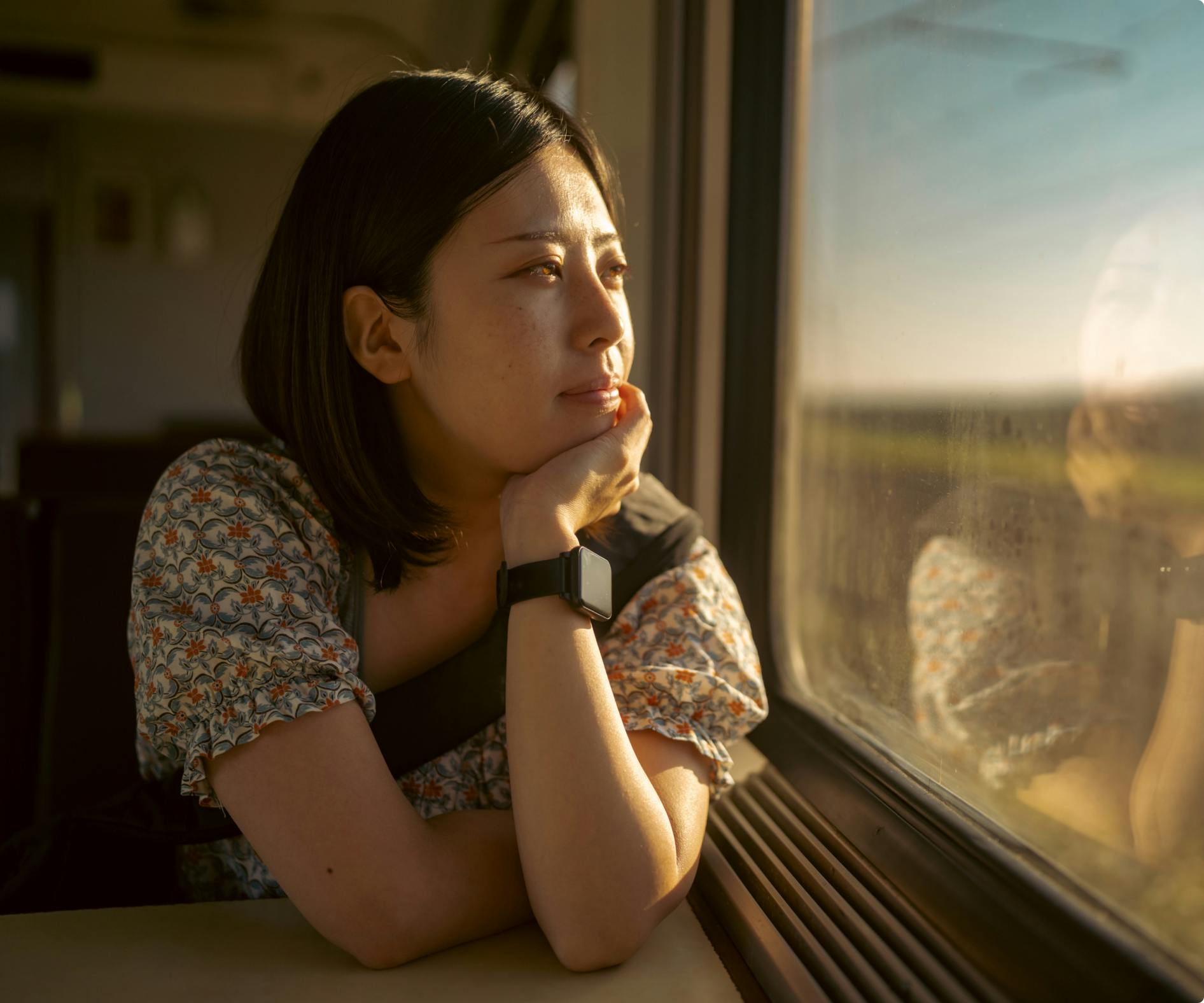 woman looking out of window at countryside while sitting on train