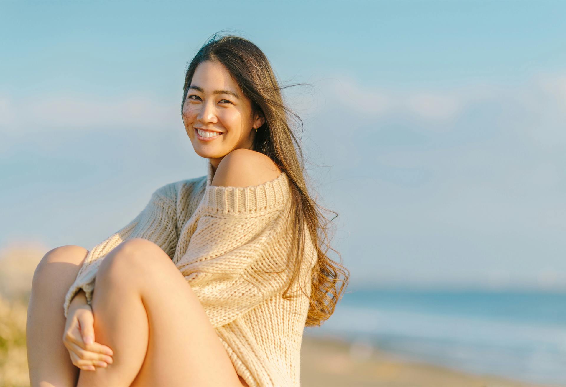 woman sitting on the beach with her legs crossed