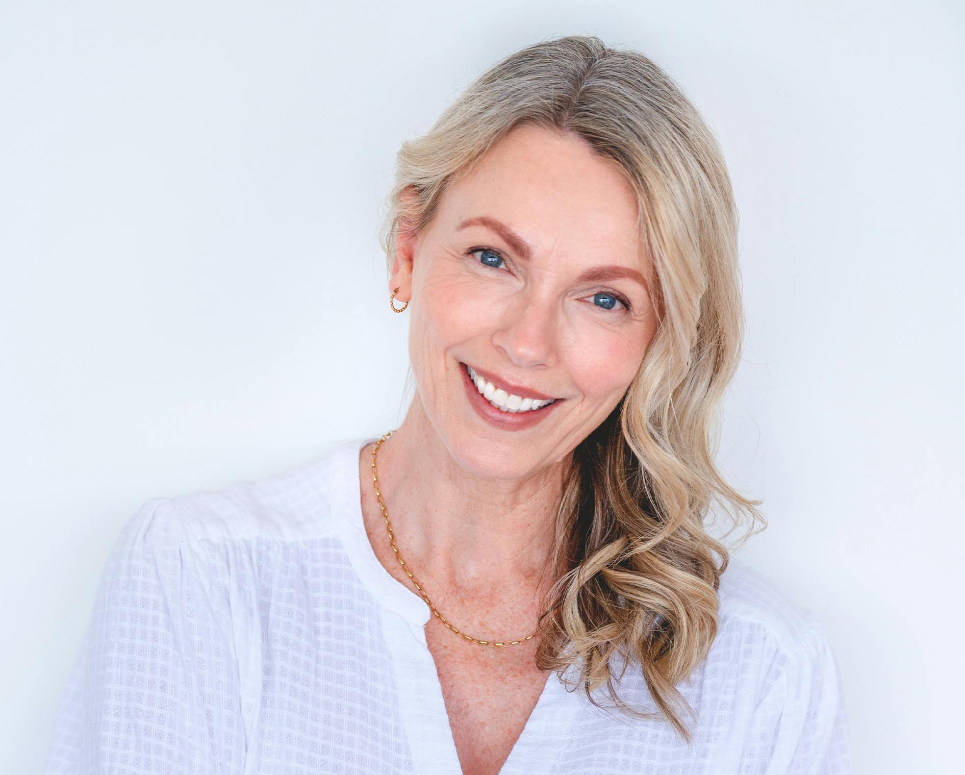 blond woman with blue eyes and a white shirt smiling