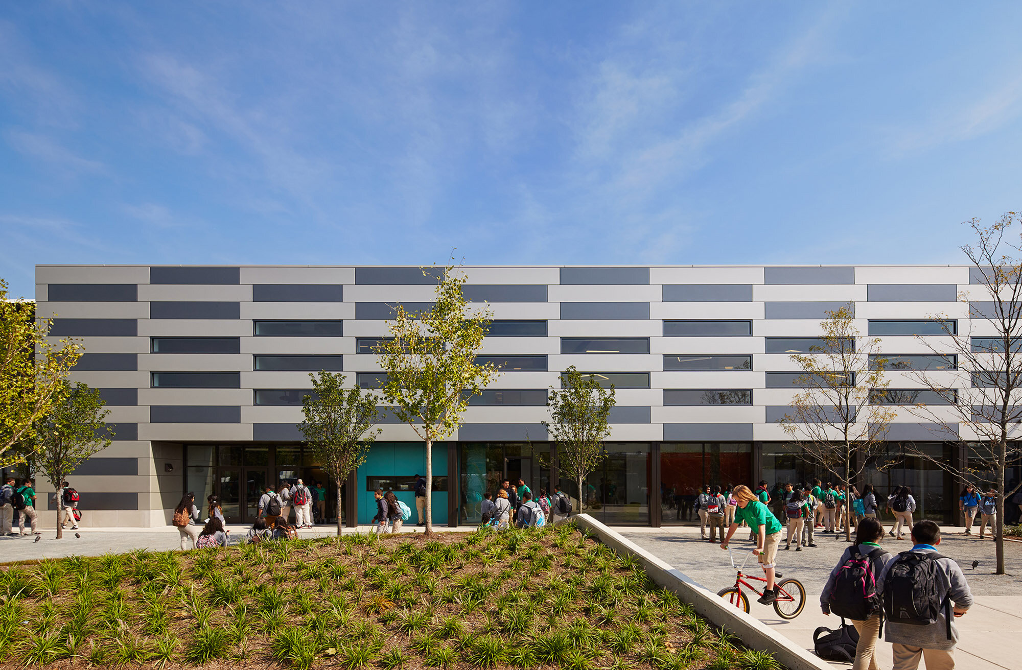 Exterior view of the Intrinsic School with kids in courtyard and landscape