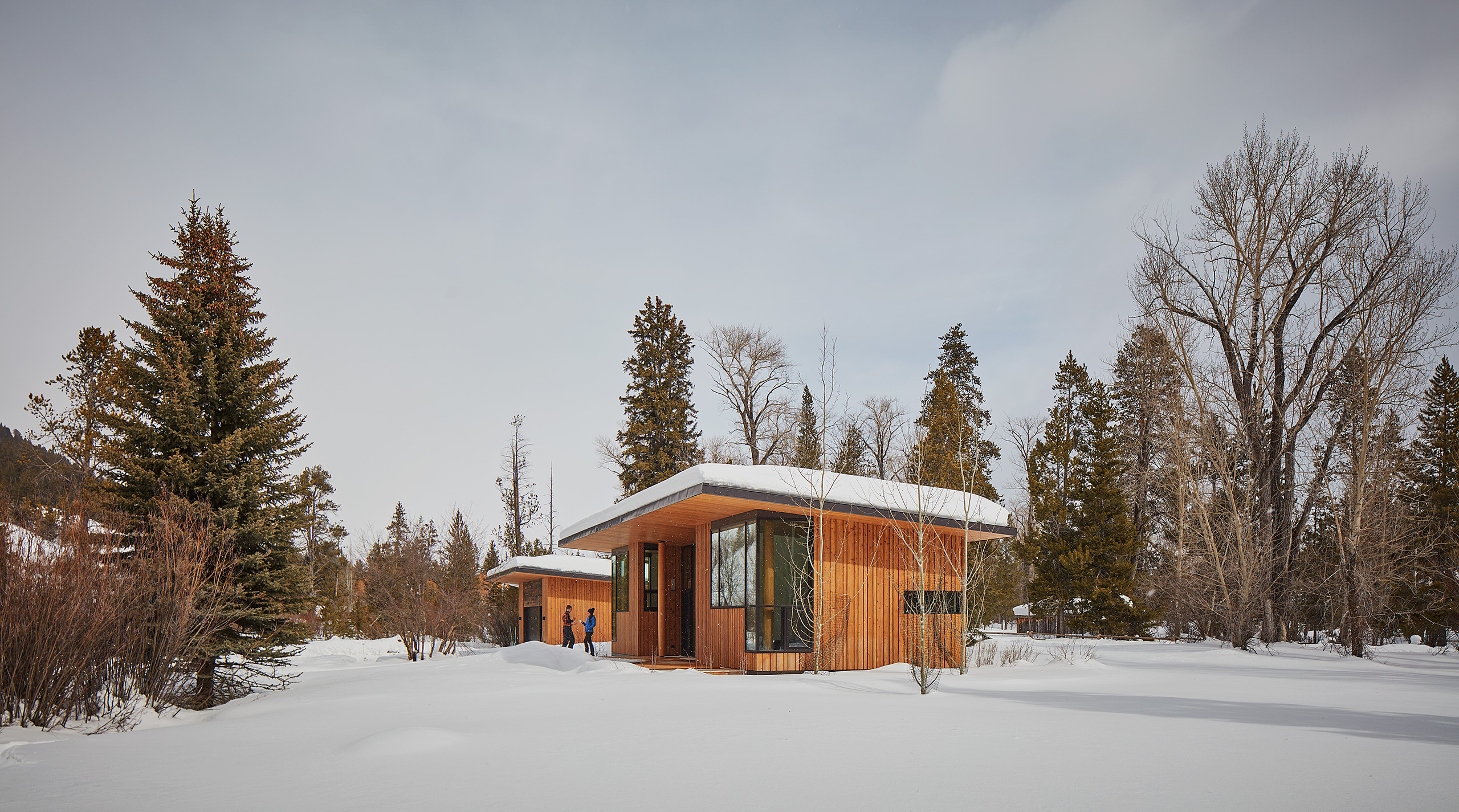 Guest house and garage in the snow with guests drinking coffee