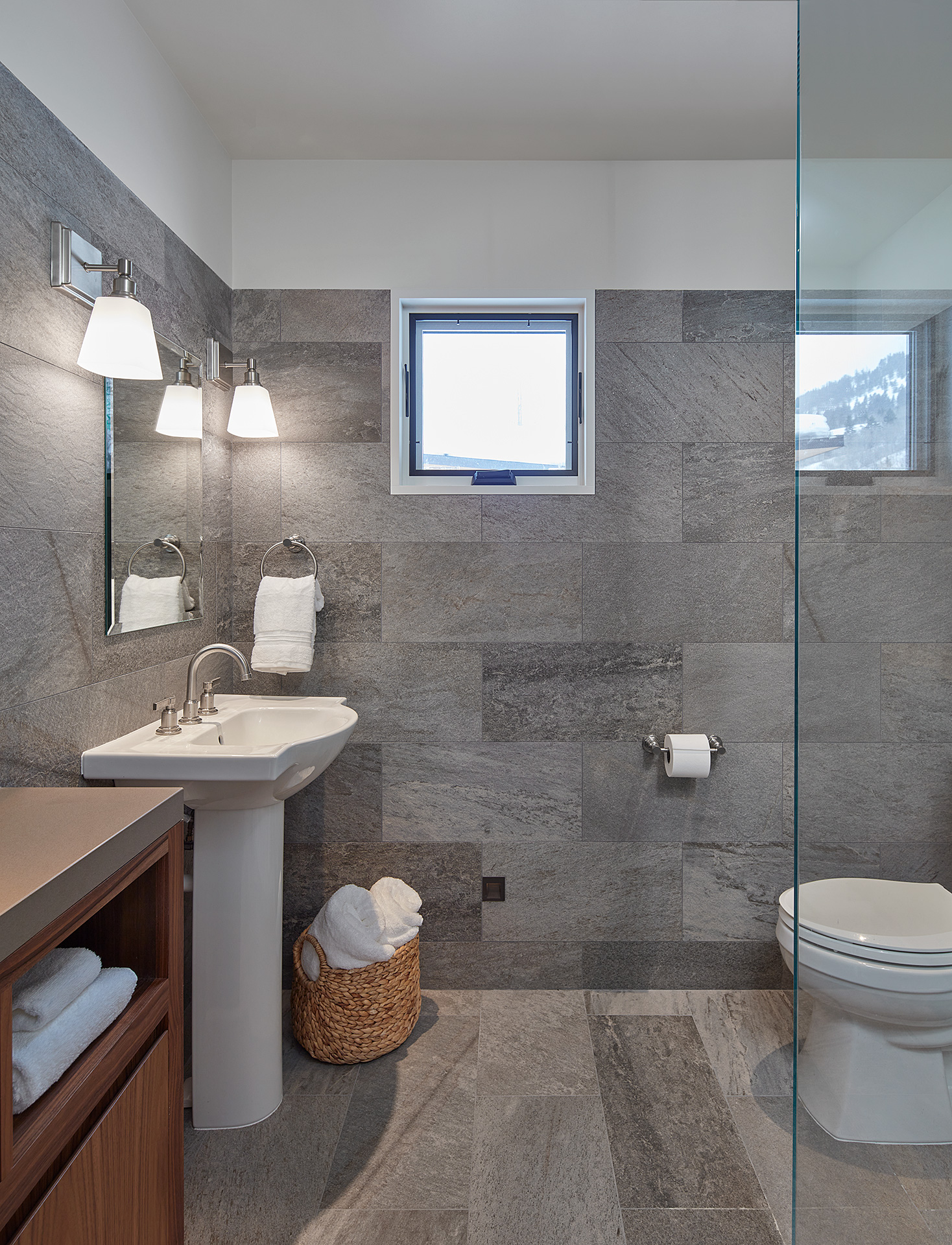 bathroom with gray slate walls, sink, toilet, and shower