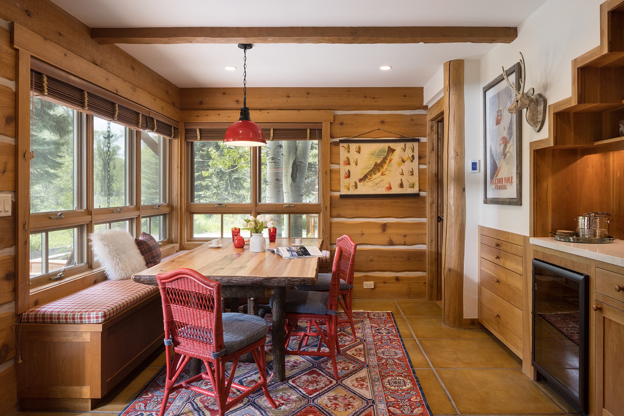 dining room with bench seat and red chairs in a cabin