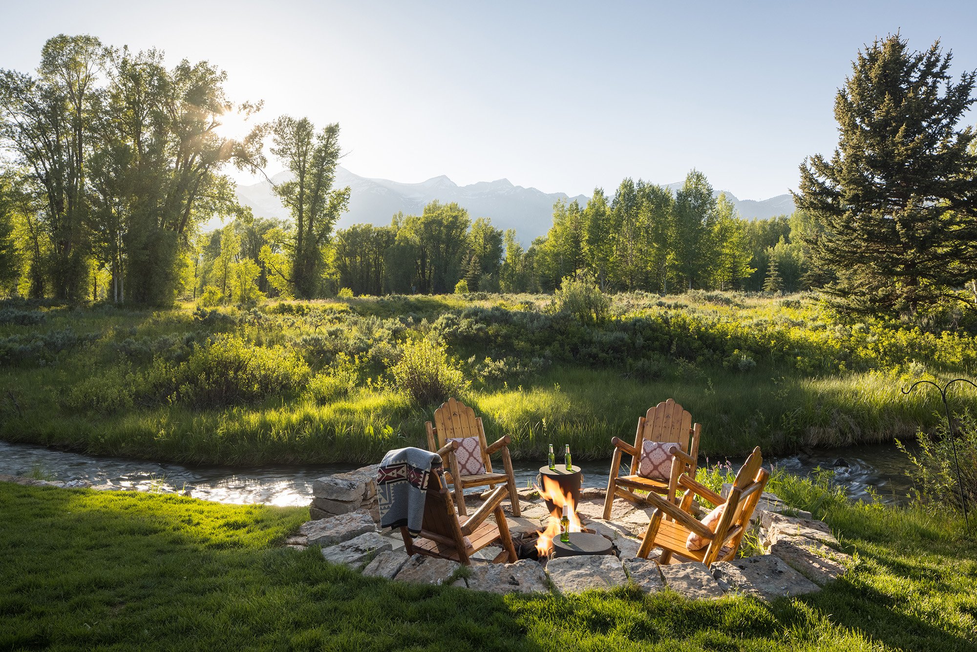 Fire pit with Adirondak Chairs in front of a creek