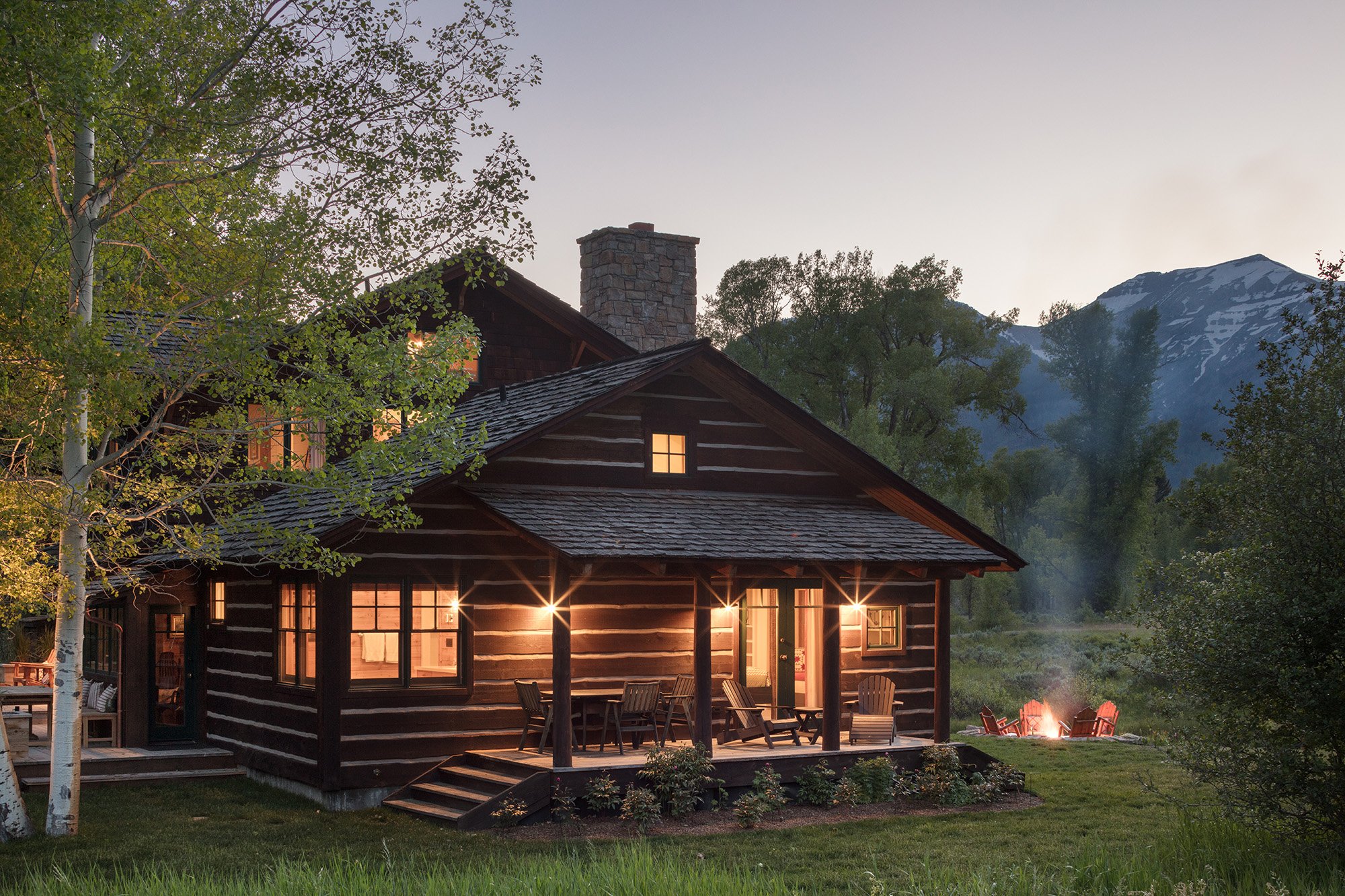 Cabin at dusk with outside firepit and mountains