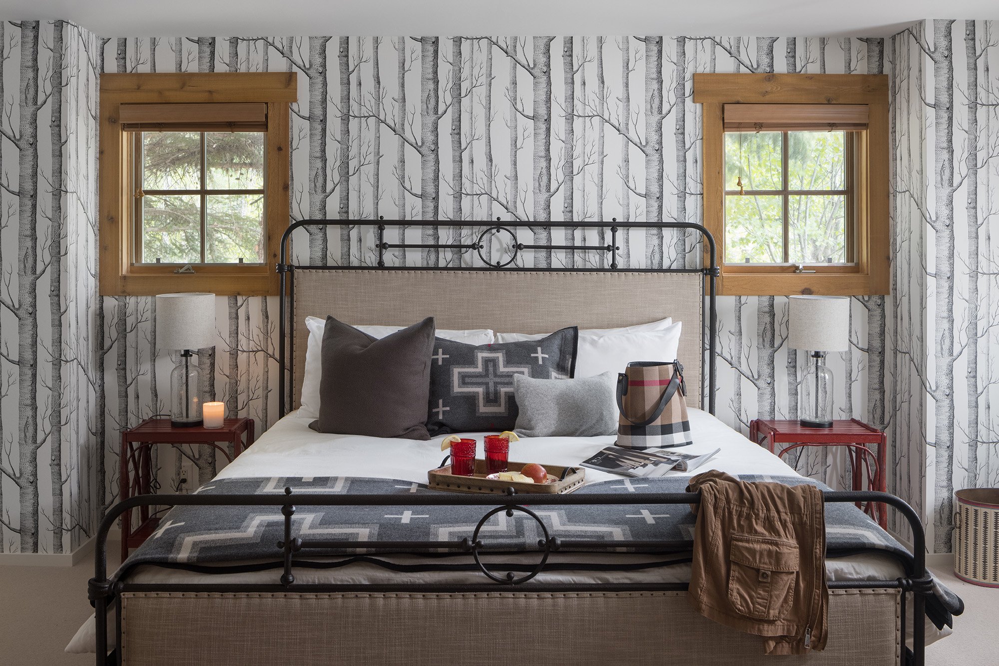 King size bed decorated in cabin like textiles with woods wallpaper