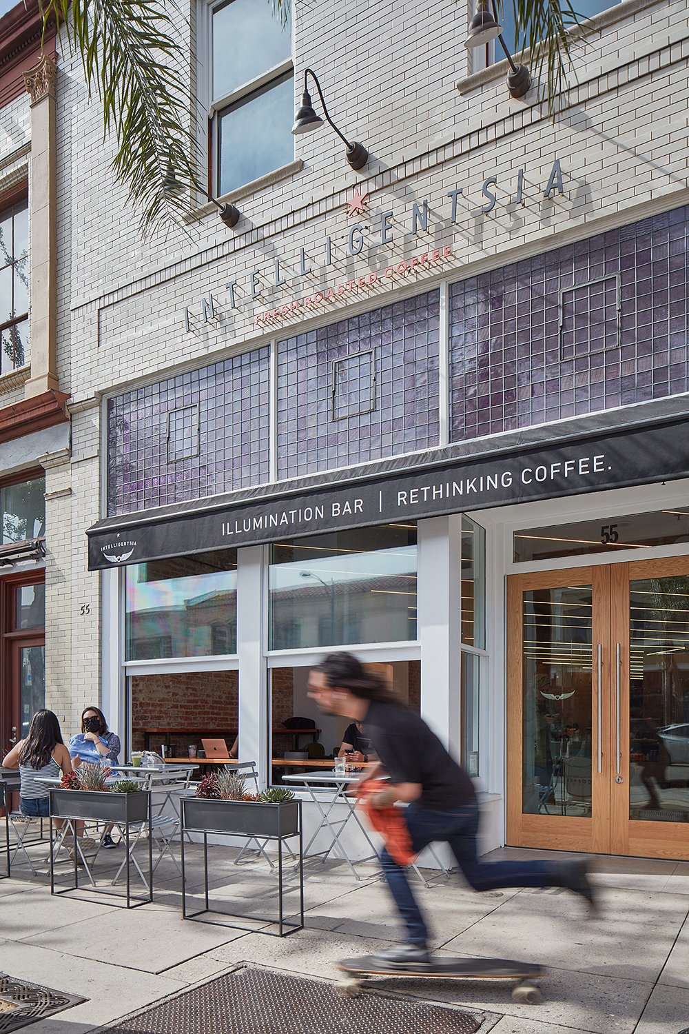 Man skateboarding on a sidewalk in front of Intelligentsia's Coffee Shop in California