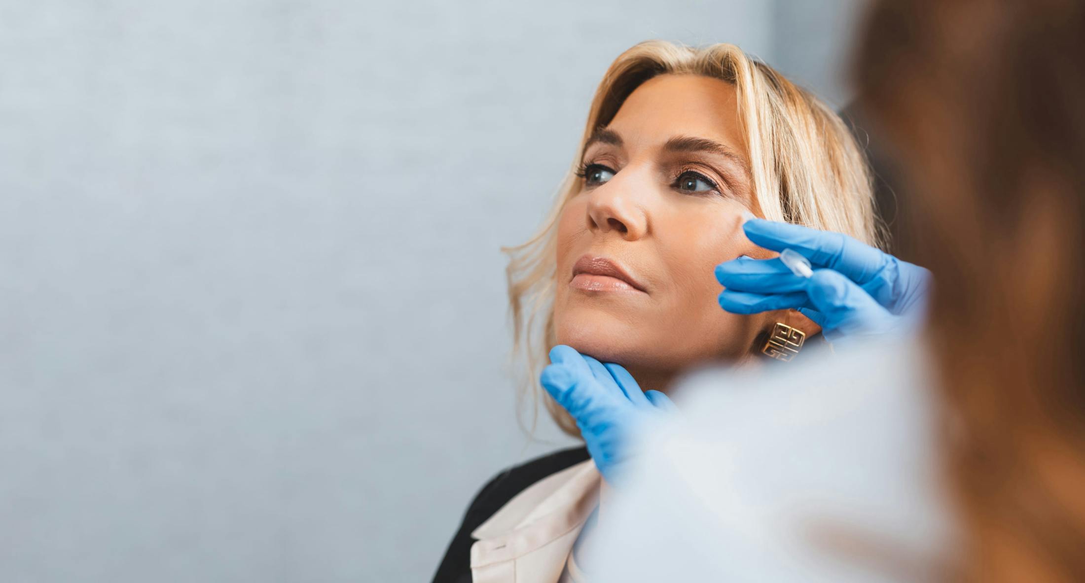 Woman looking toward the ceiling getting an injection in her cheek