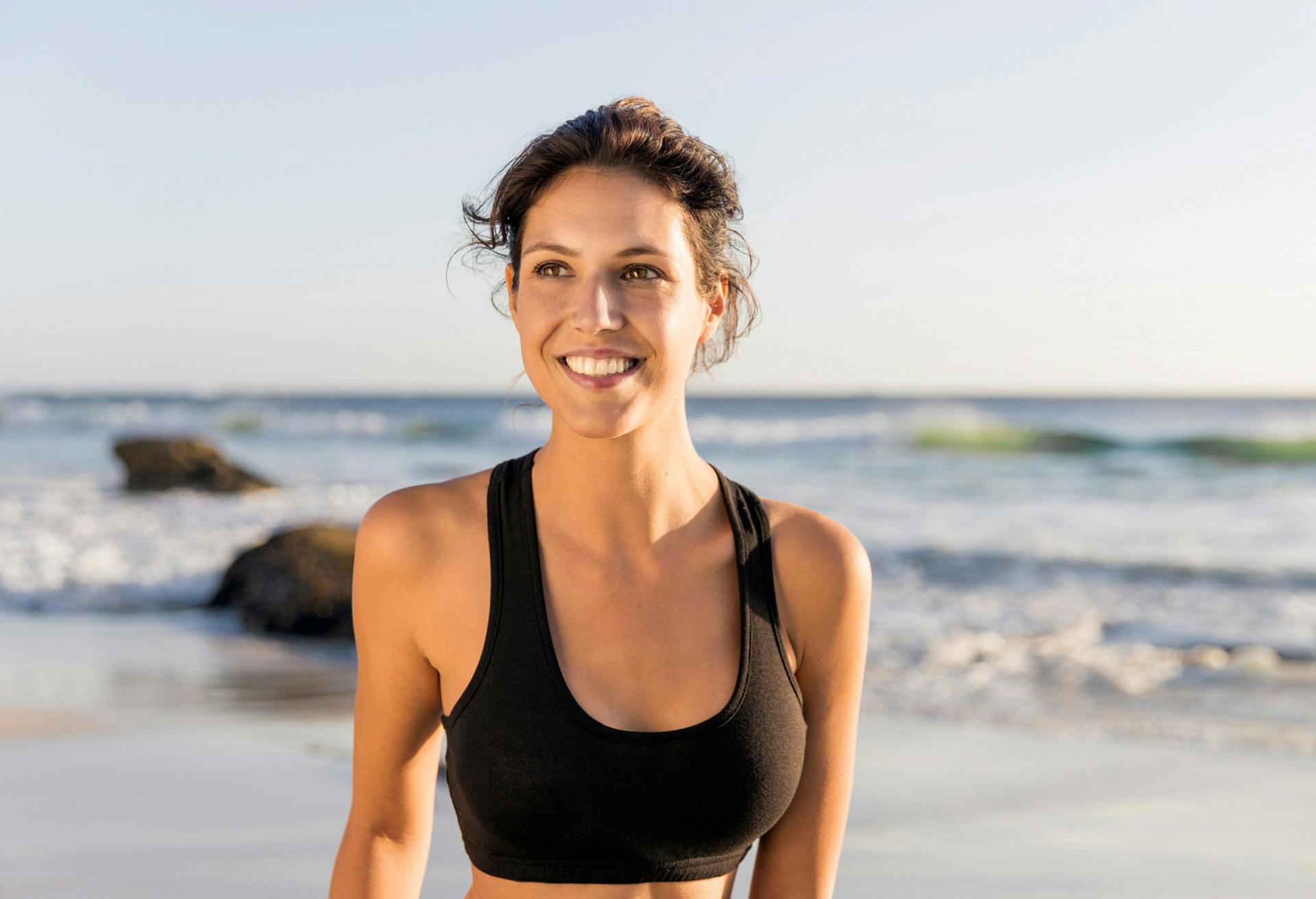 Woman in a black sports bra in front of the ocean