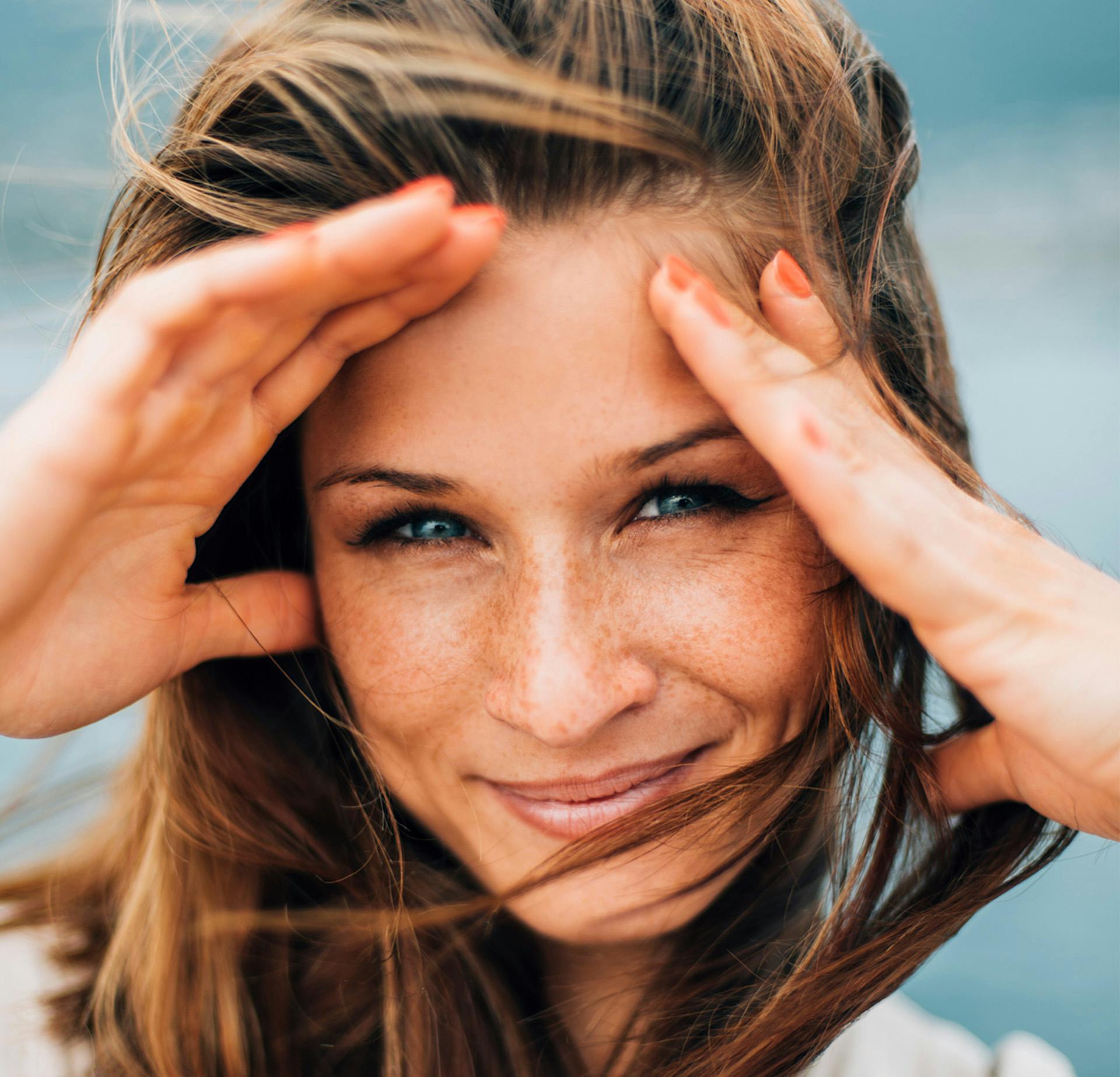 Woman smiling with her hands on her forehead