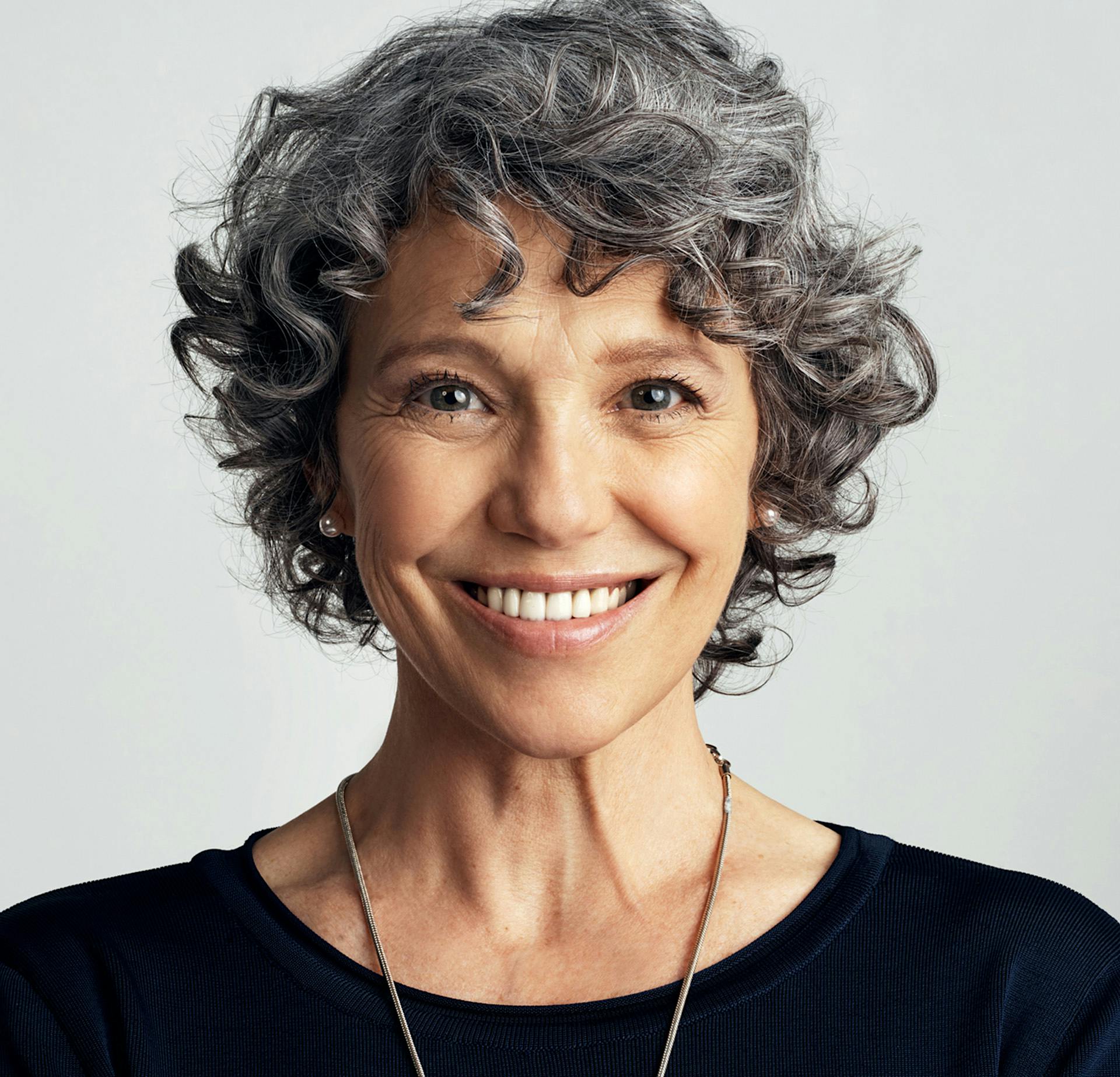 Woman with gray hair and a black shirt smiling