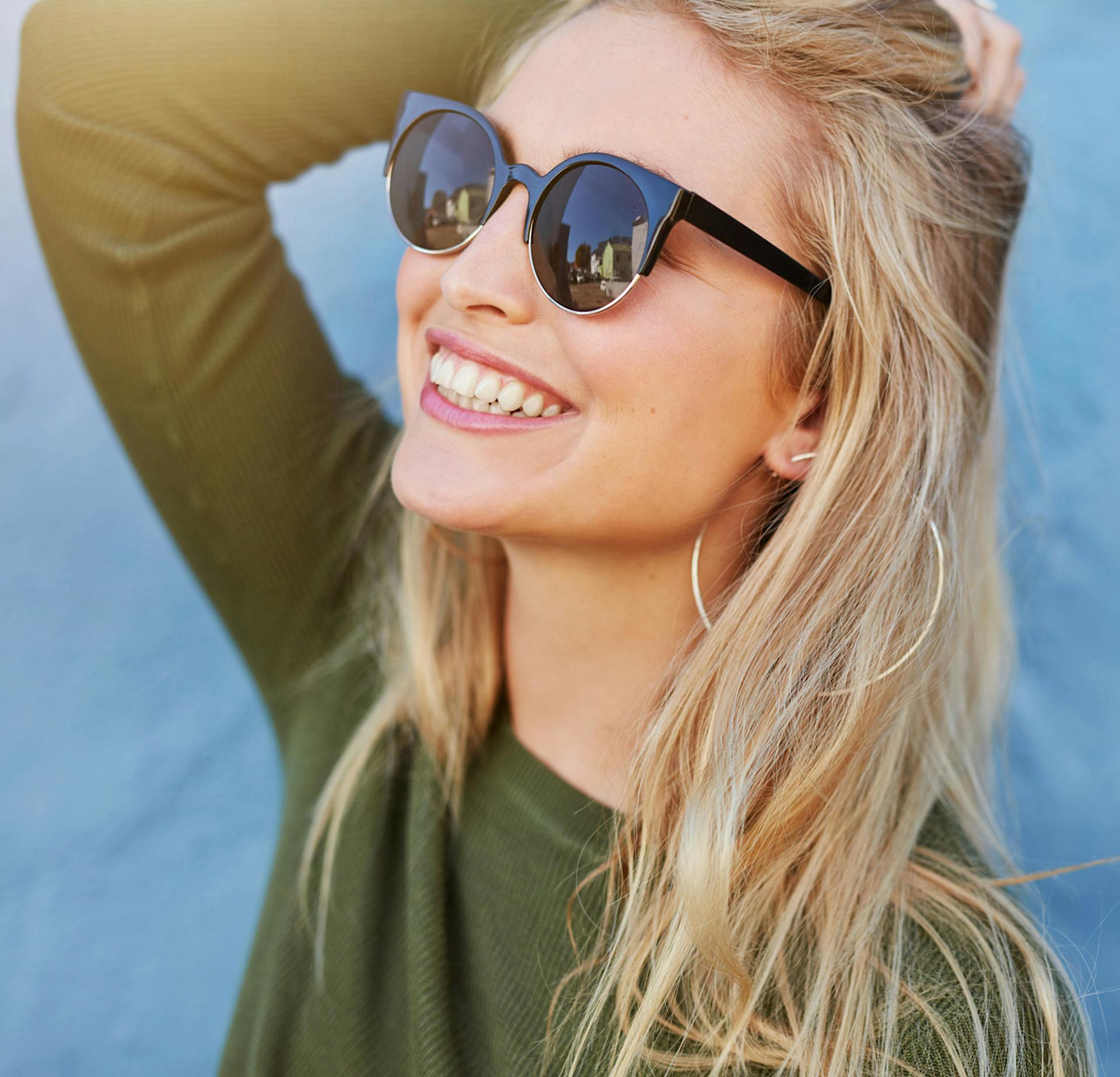 Woman in a green shirt and sunglasses smiling