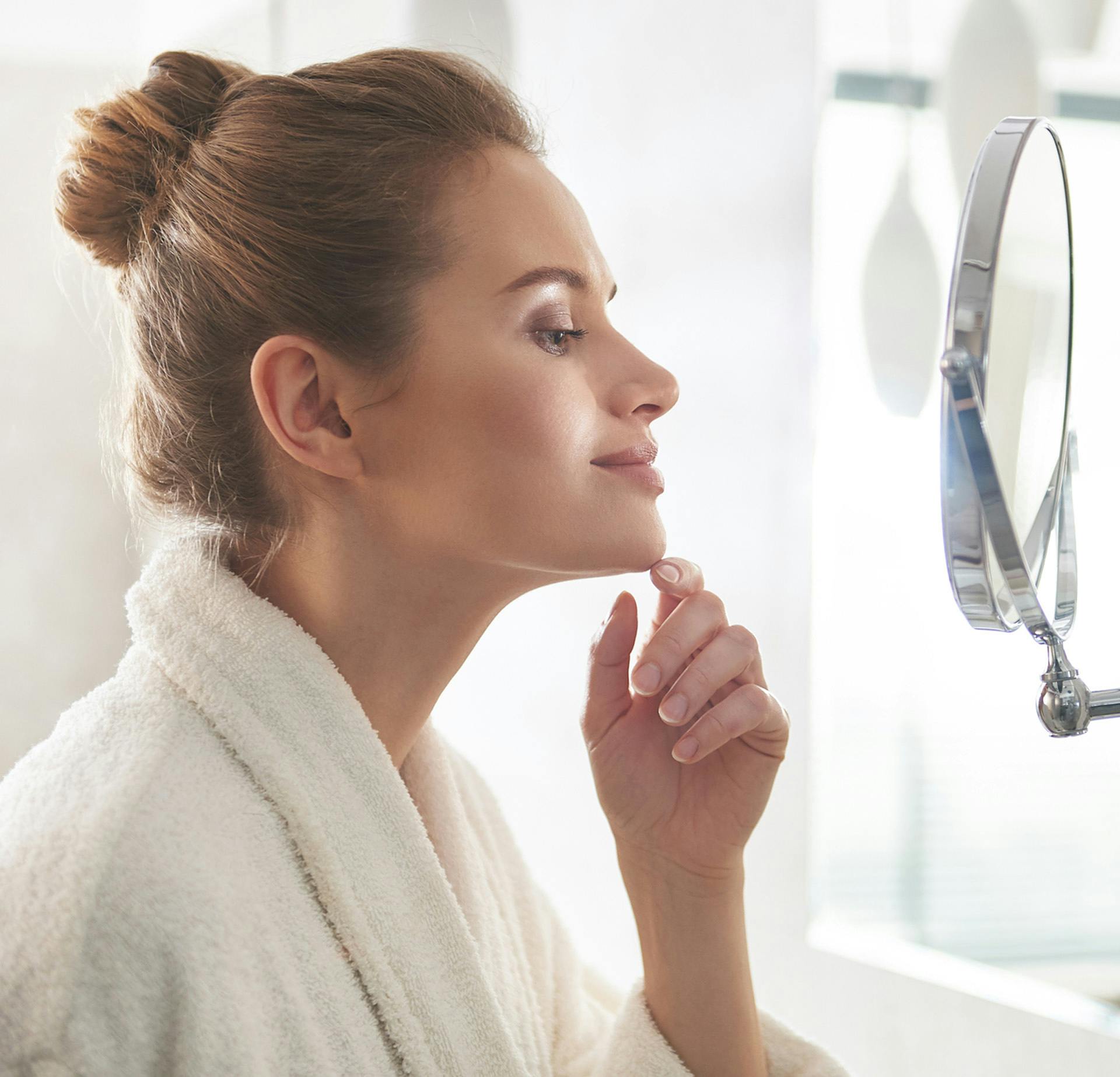 Woman looking in the mirror with her hand on her chin