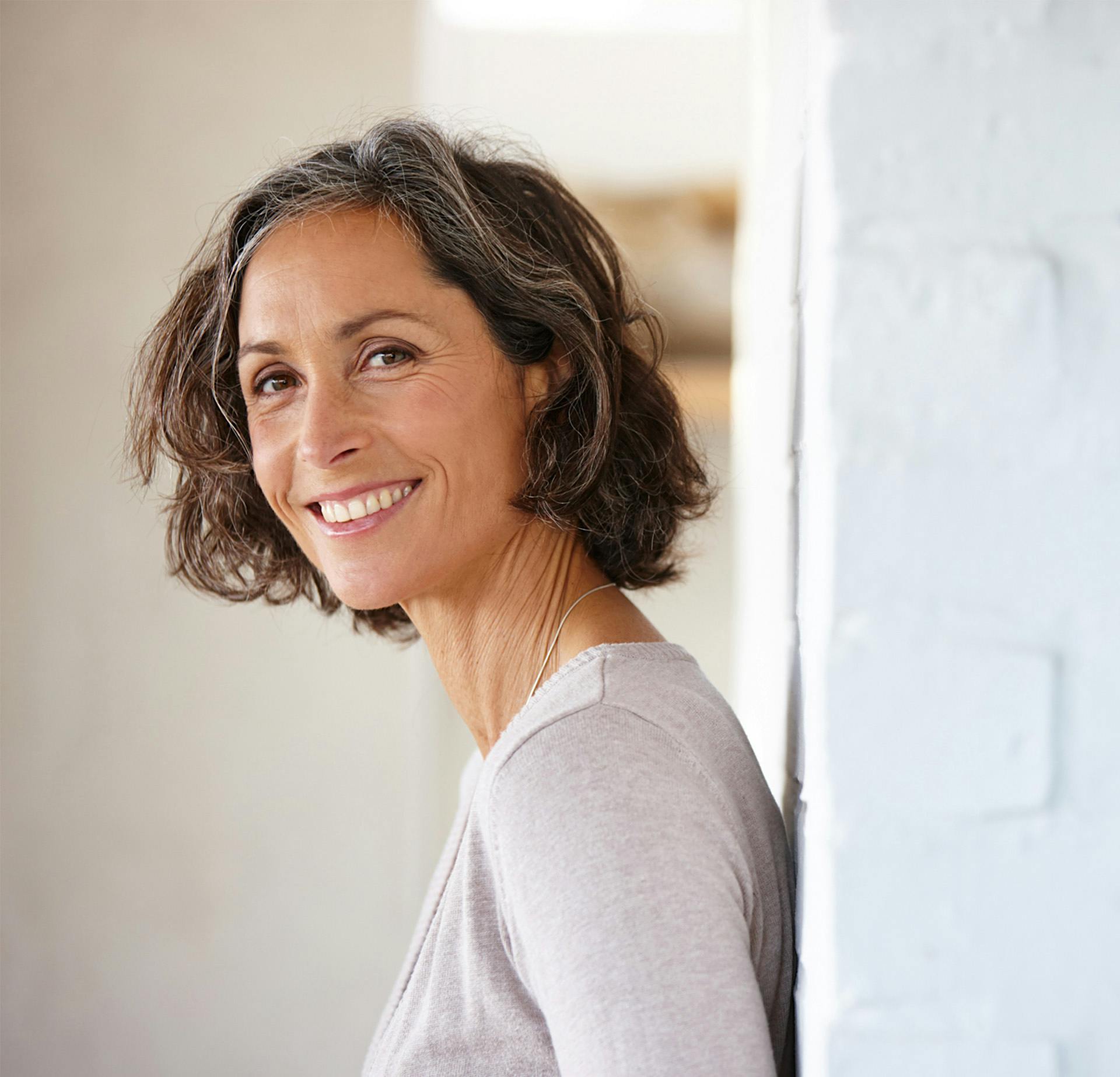Woman leaning up against a wall and smiling