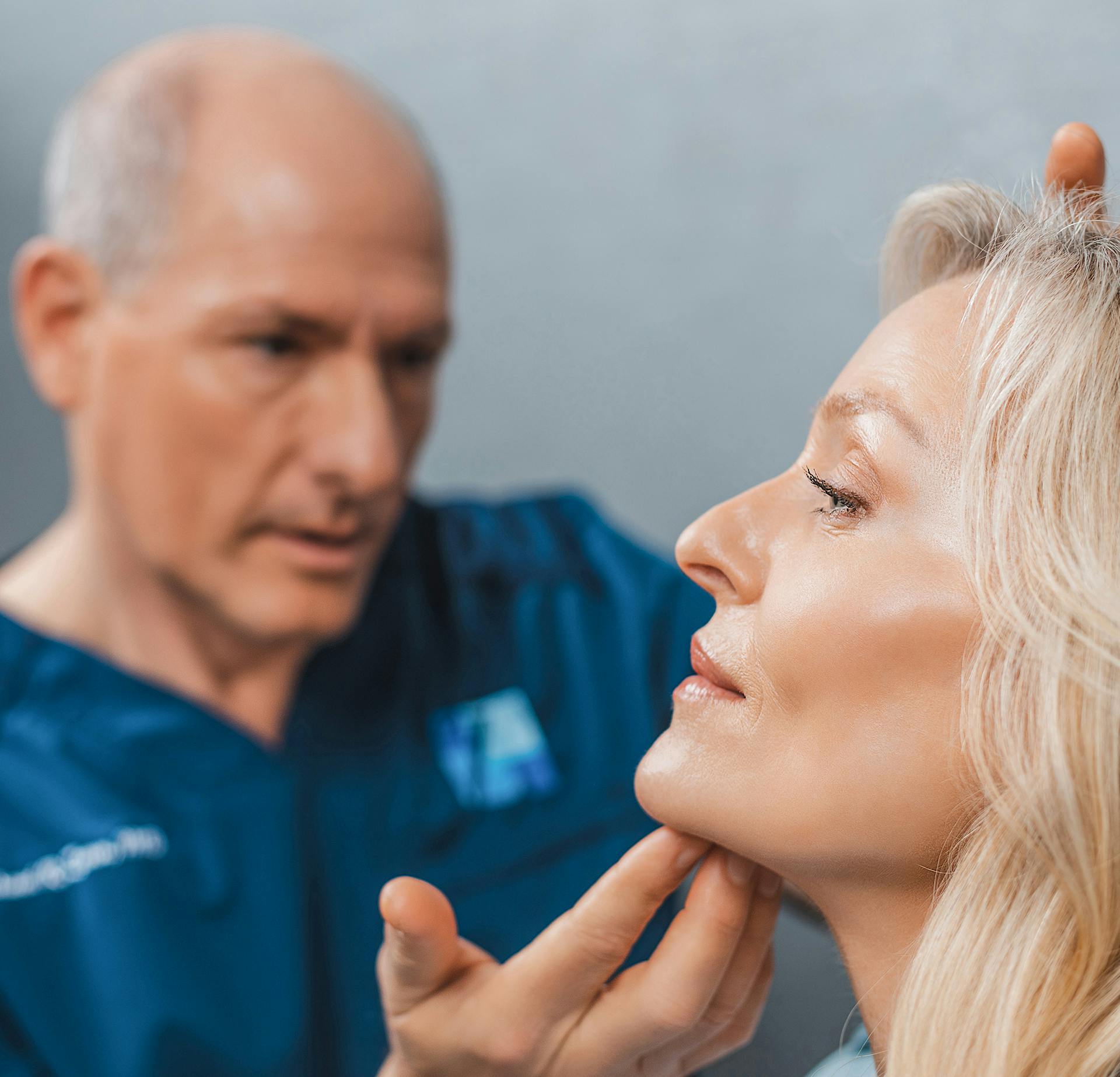 Dr. Zenn with his hand on a womans chin, observing her face