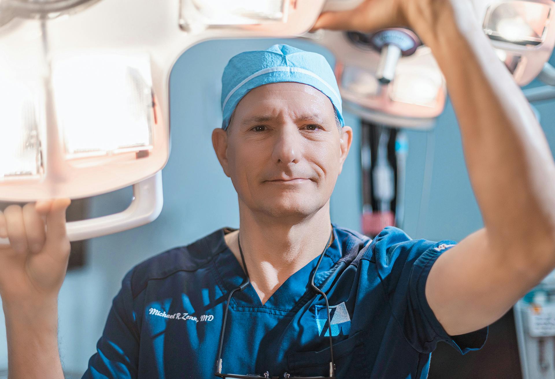 Dr. Zenn in the operating room with his hands up on equipment