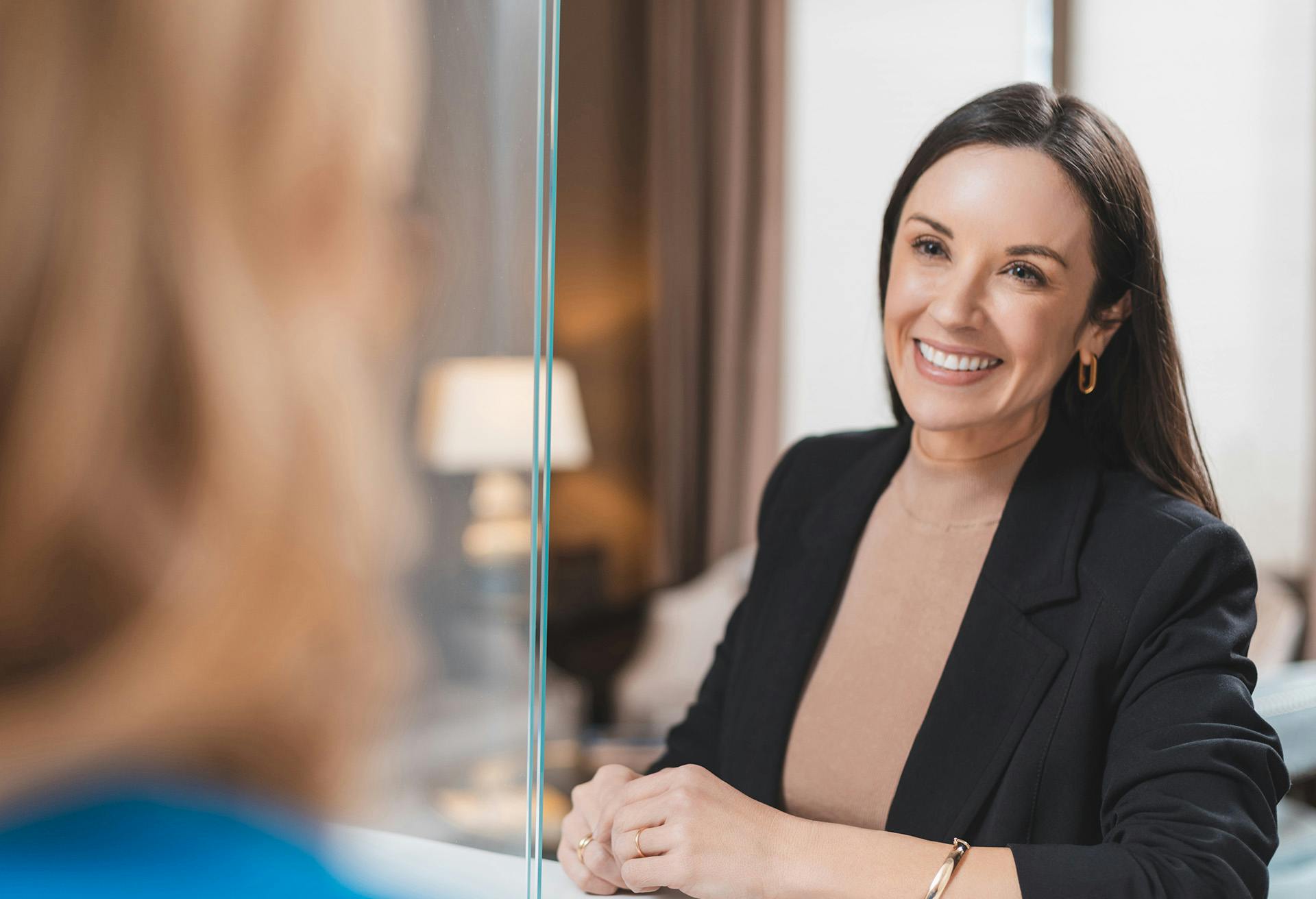 Woman in a black blazer smiling at another woman