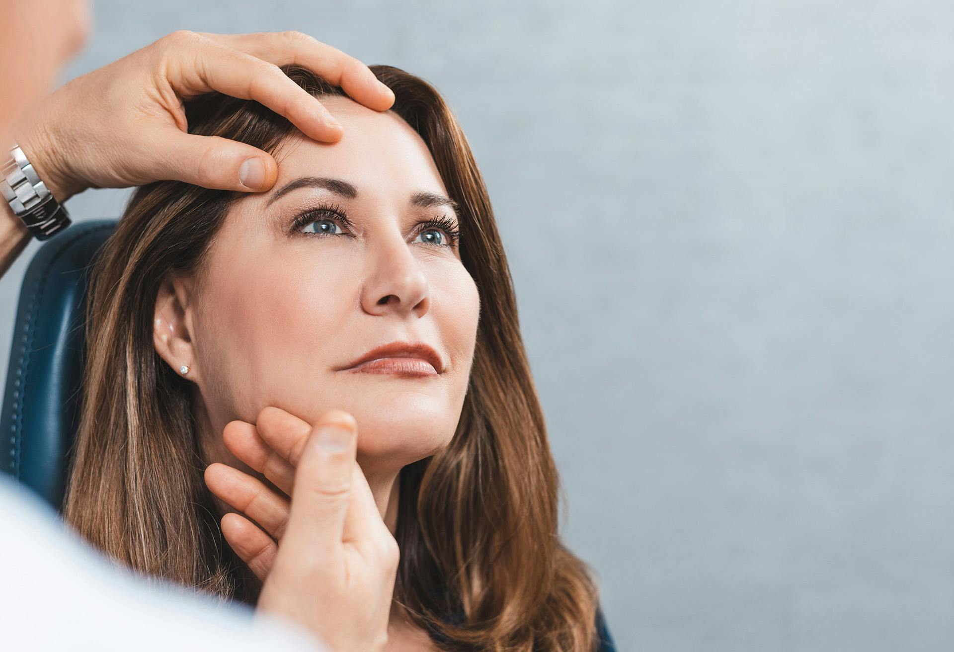 Woman getting her eyebrows looked at by a doctor