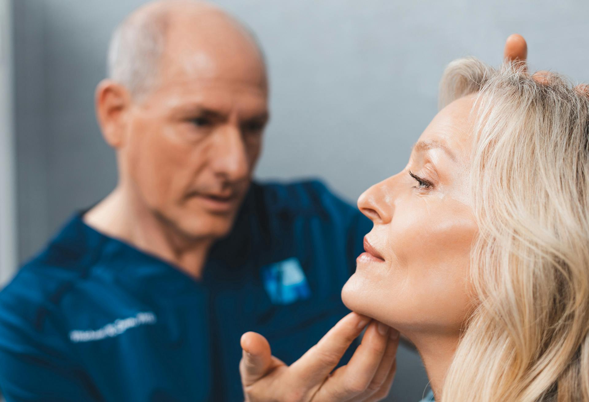 Dr. Zenn examining a patients face with his hand on her chin