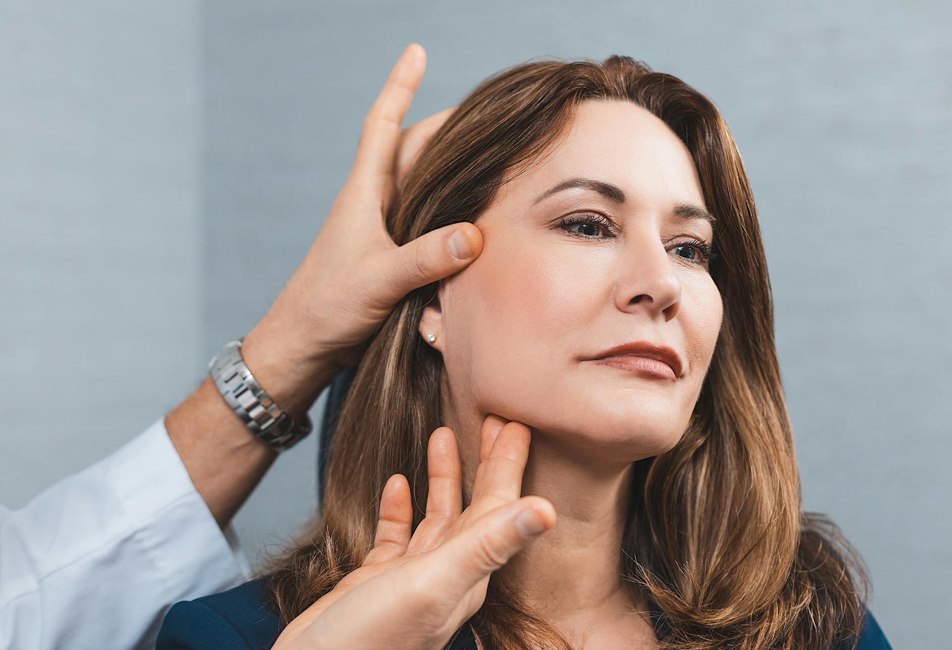 Woman getting examined with doctors hands on her chin and cheek