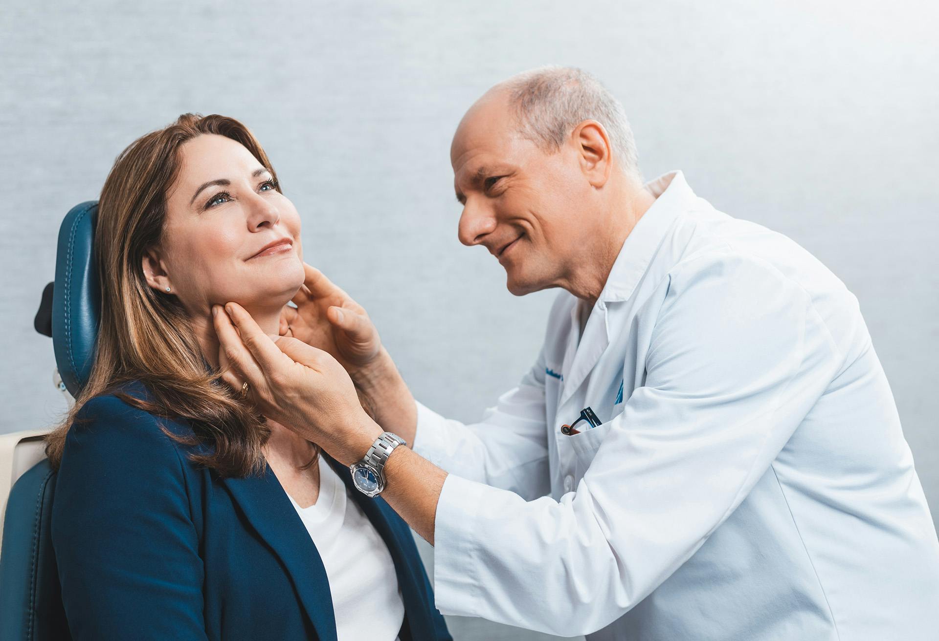 Dr. Zenn looking at a patients face with his hand on her chin