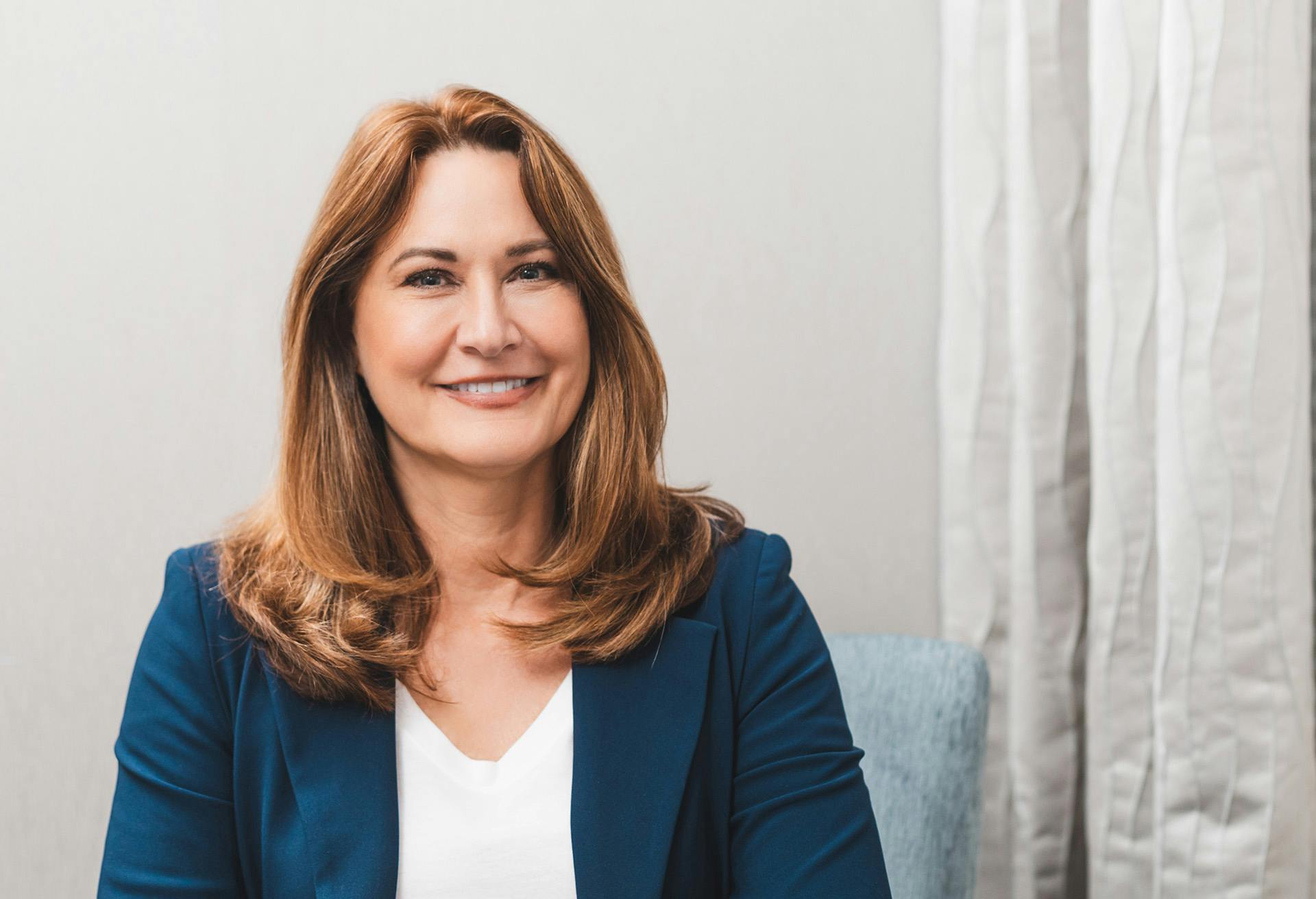 Woman in a blue blazer sitting in a chair, smiling