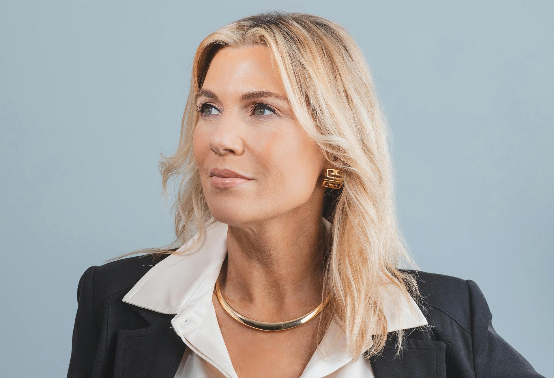 Blonde woman in a black blazer looking to the left