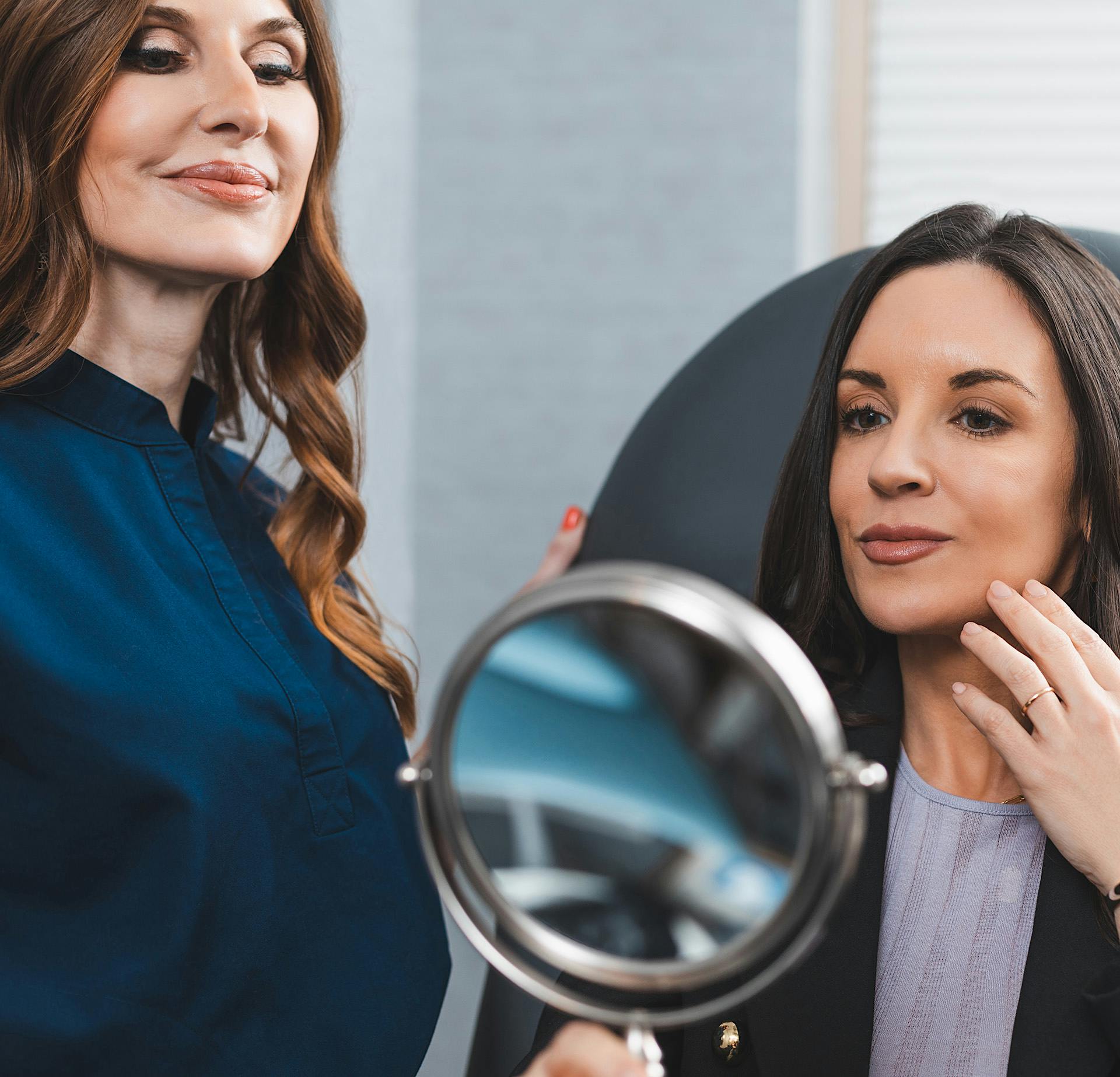 Woman looking at herself in the mirror with Tara Cypher looking as well