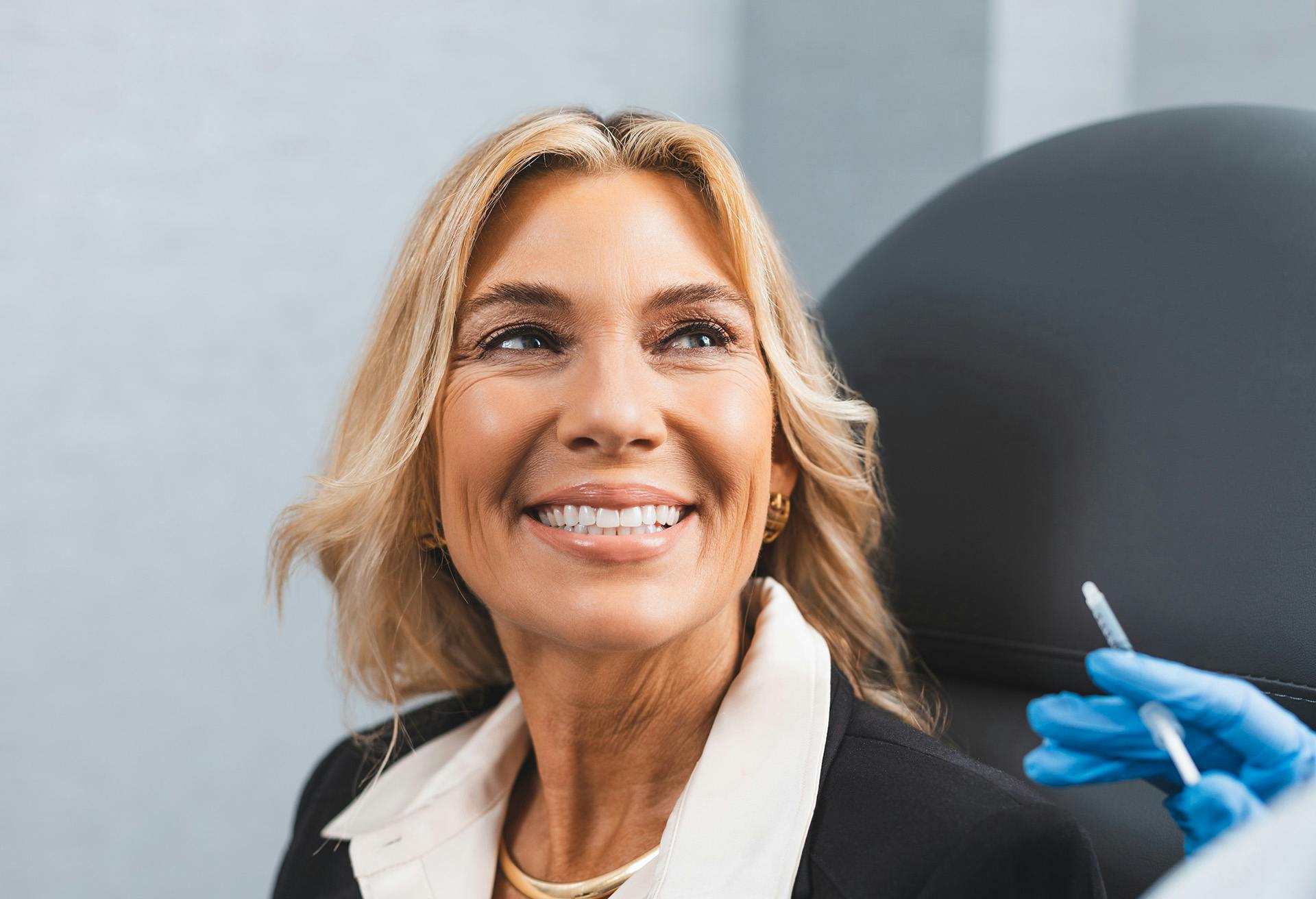 Woman in a chair getting ready to receive facial injections