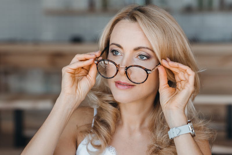A woman holding her glasses