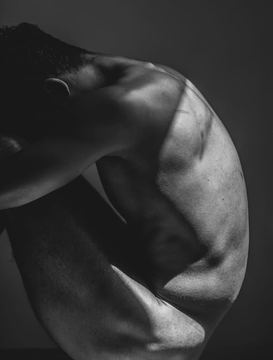 Side view of a Nude man crouching down